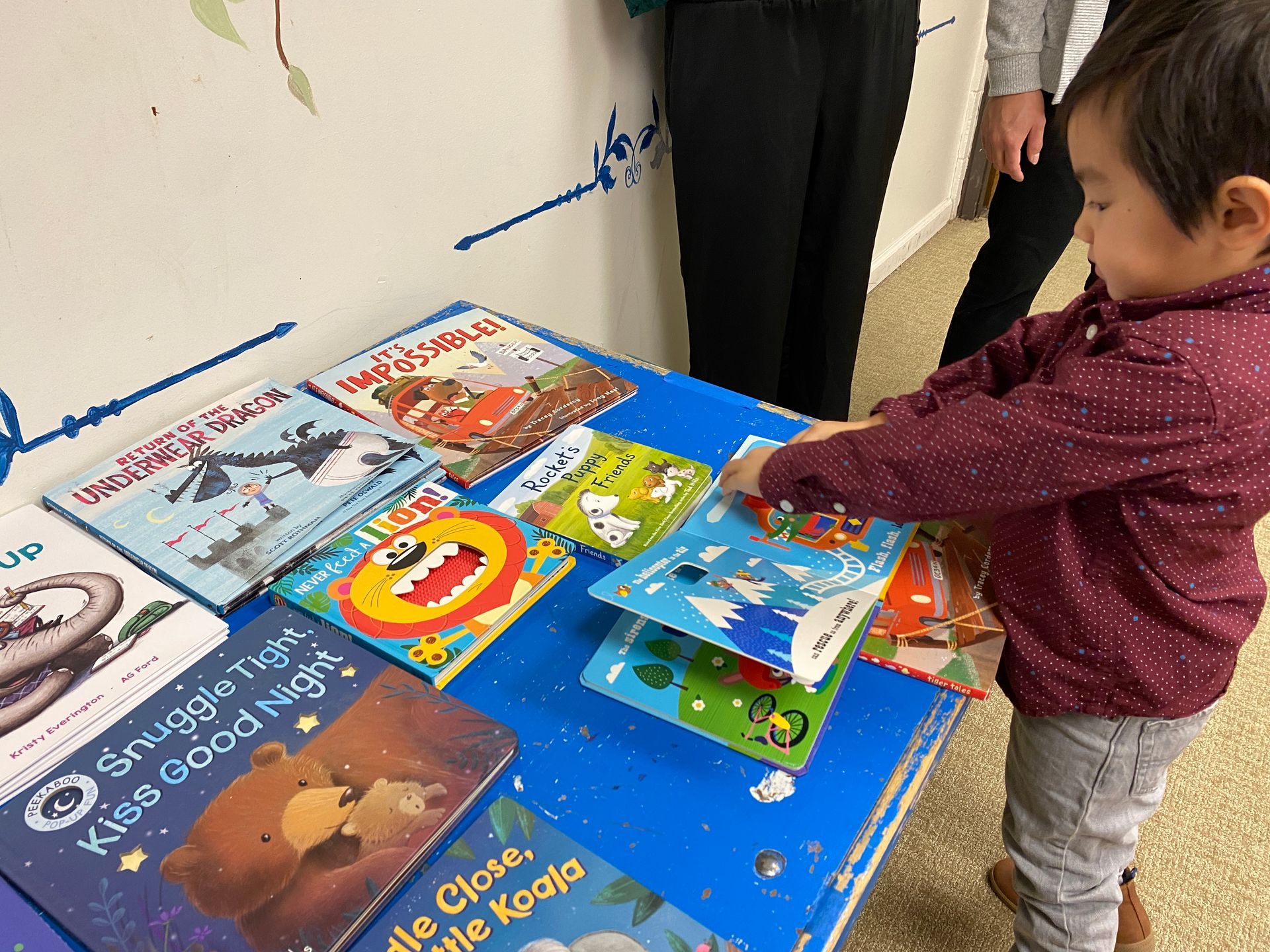 A little boy is looking at a book on a table.