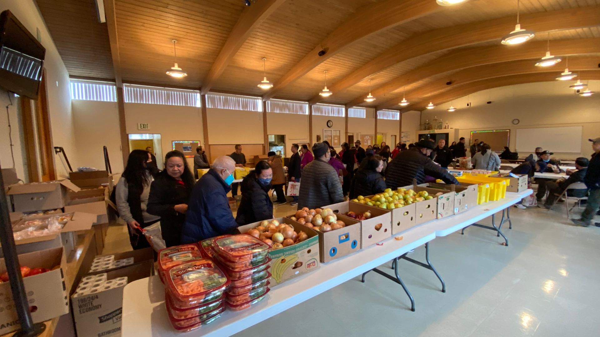 A group of people are standing around tables filled with fruits and vegetables.