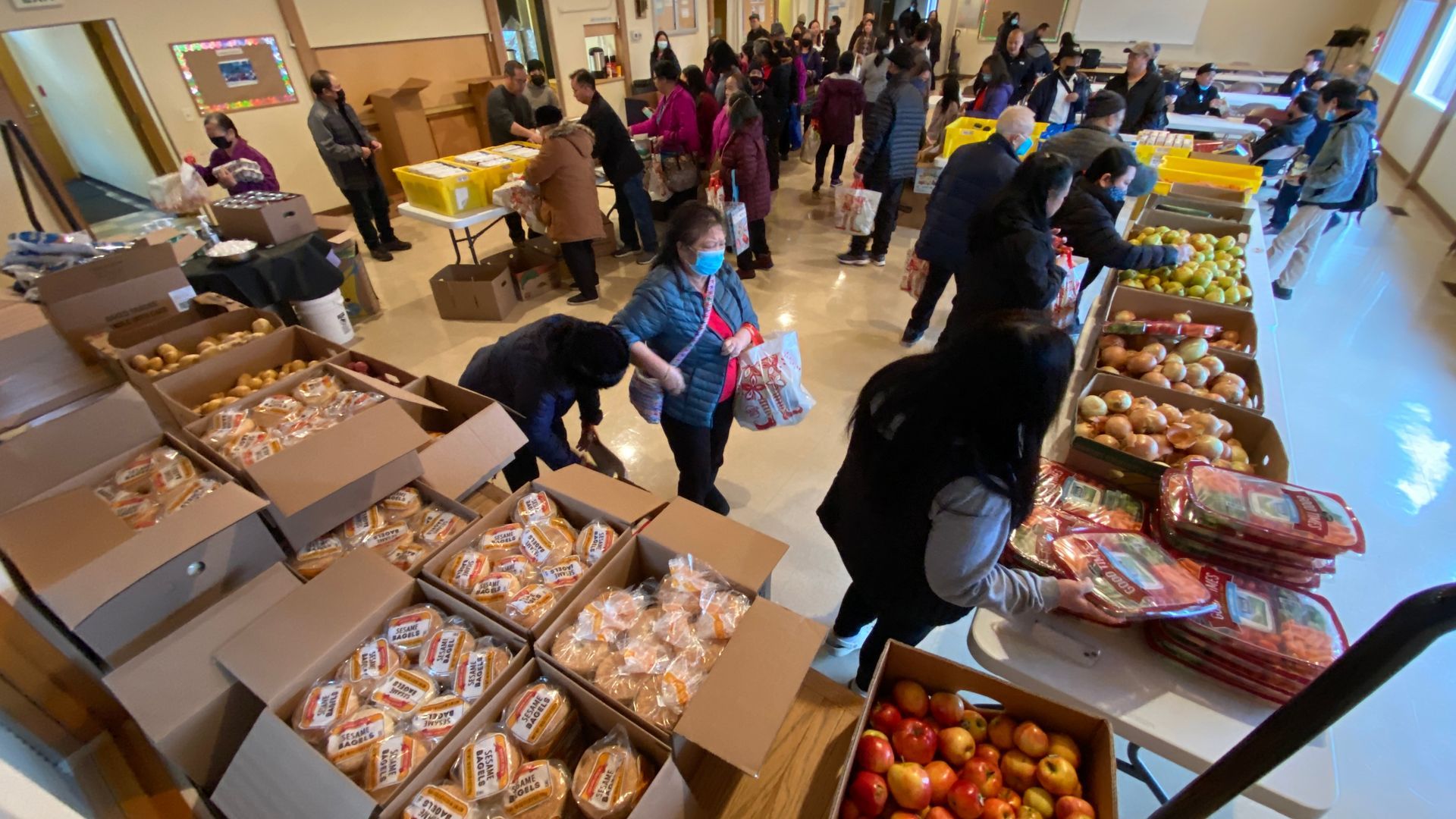A group of people are standing around a table filled with boxes of food.