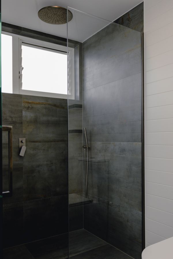 A bathroom with a walk in shower and a window.