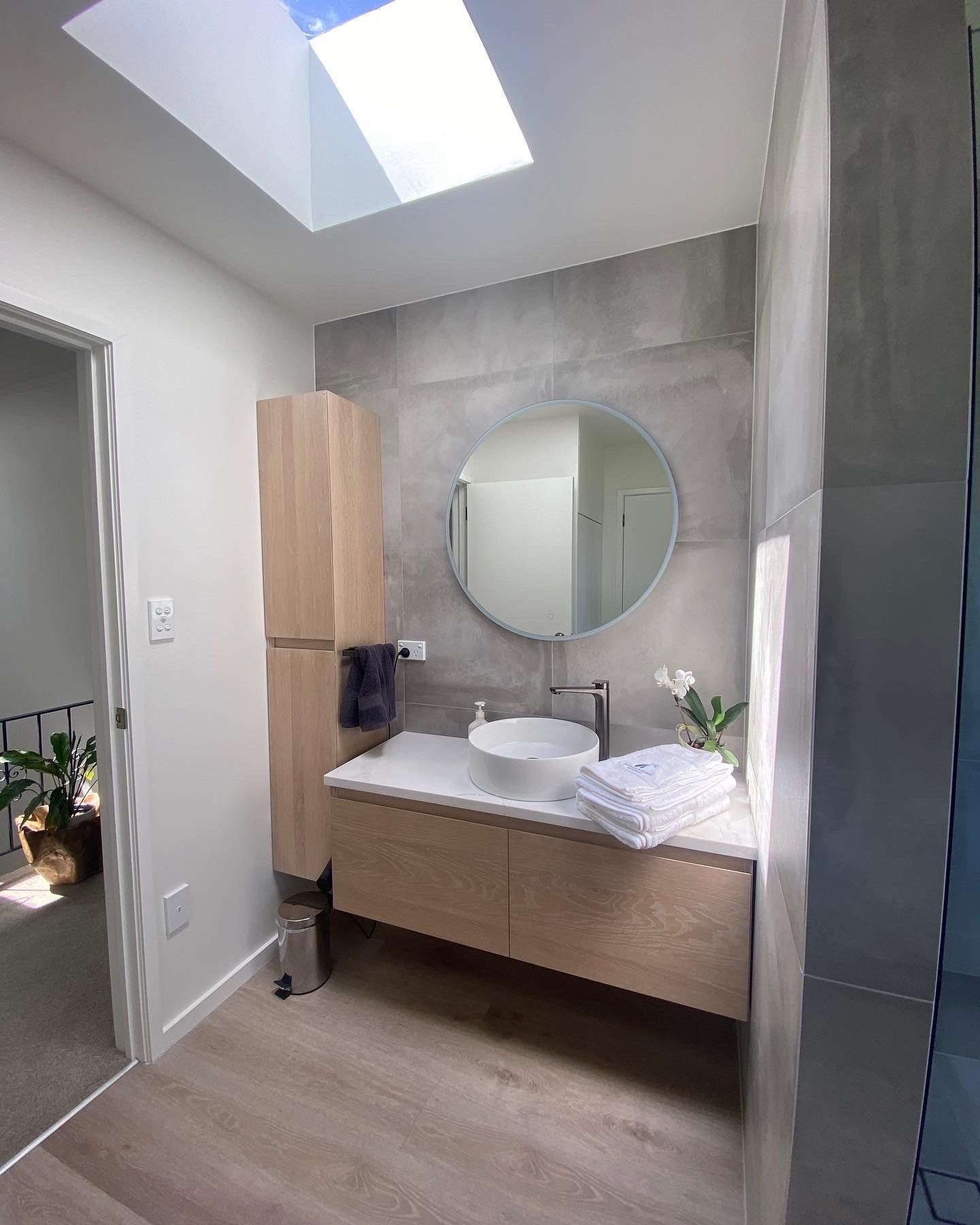 A bathroom with a sink , mirror and skylight.