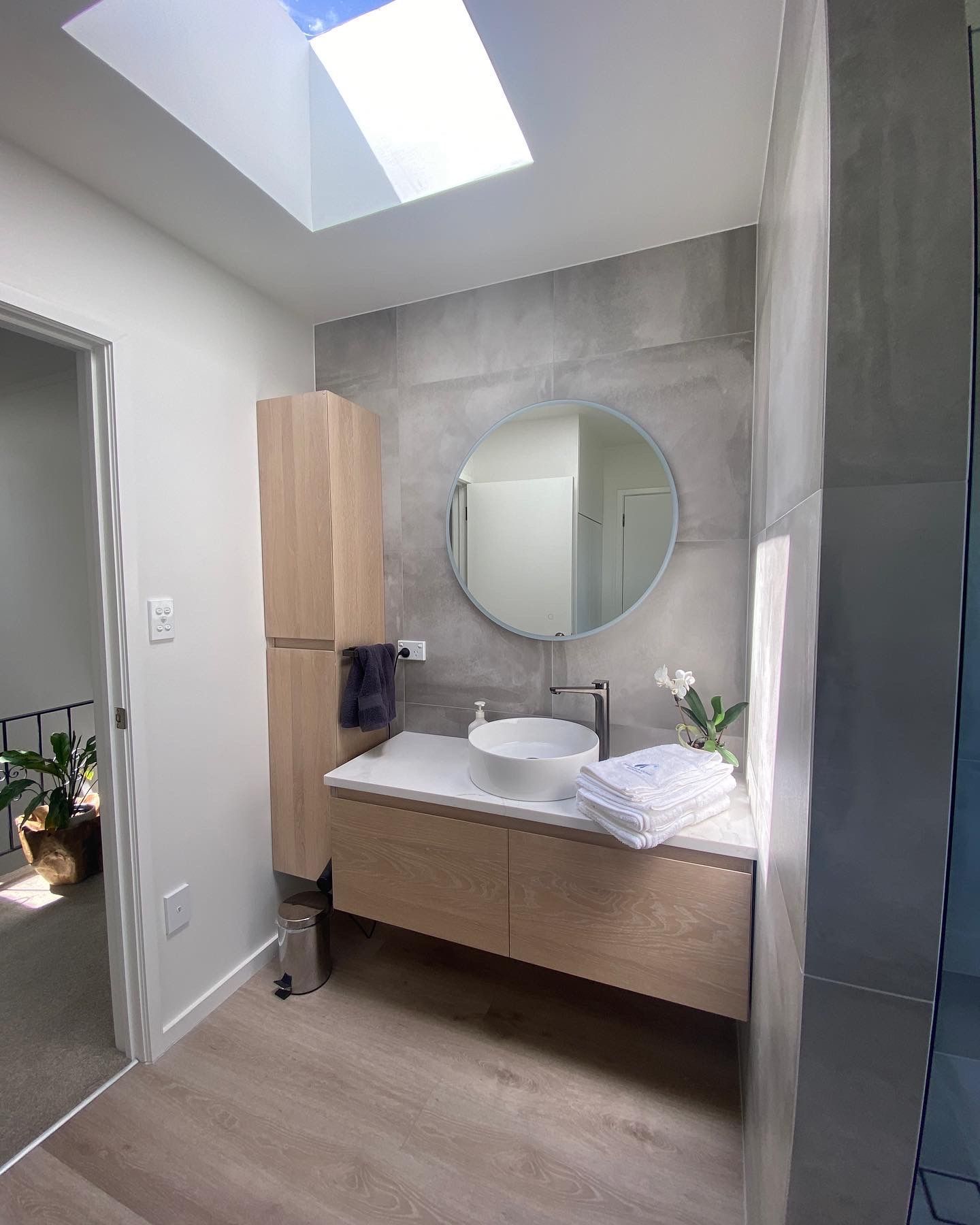 A bathroom with a sink , mirror and skylight.