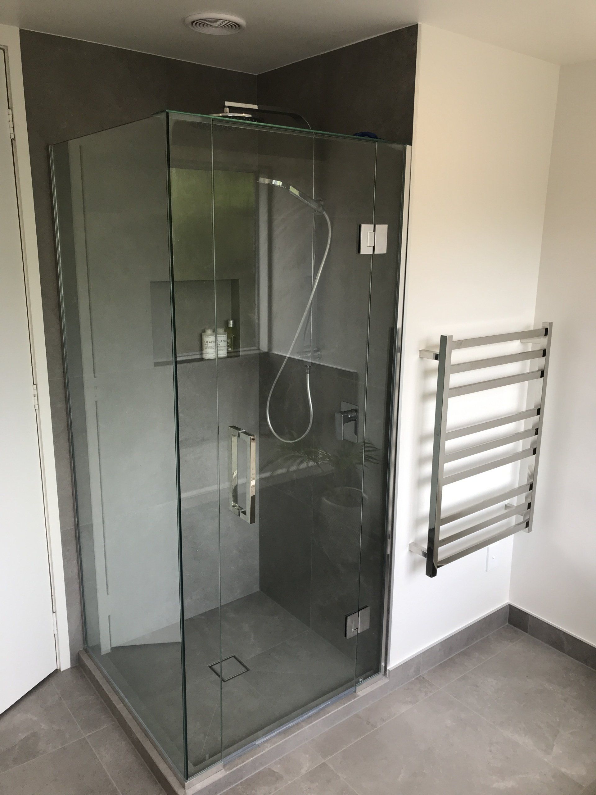 A bathroom with a walk in shower and a towel rack.