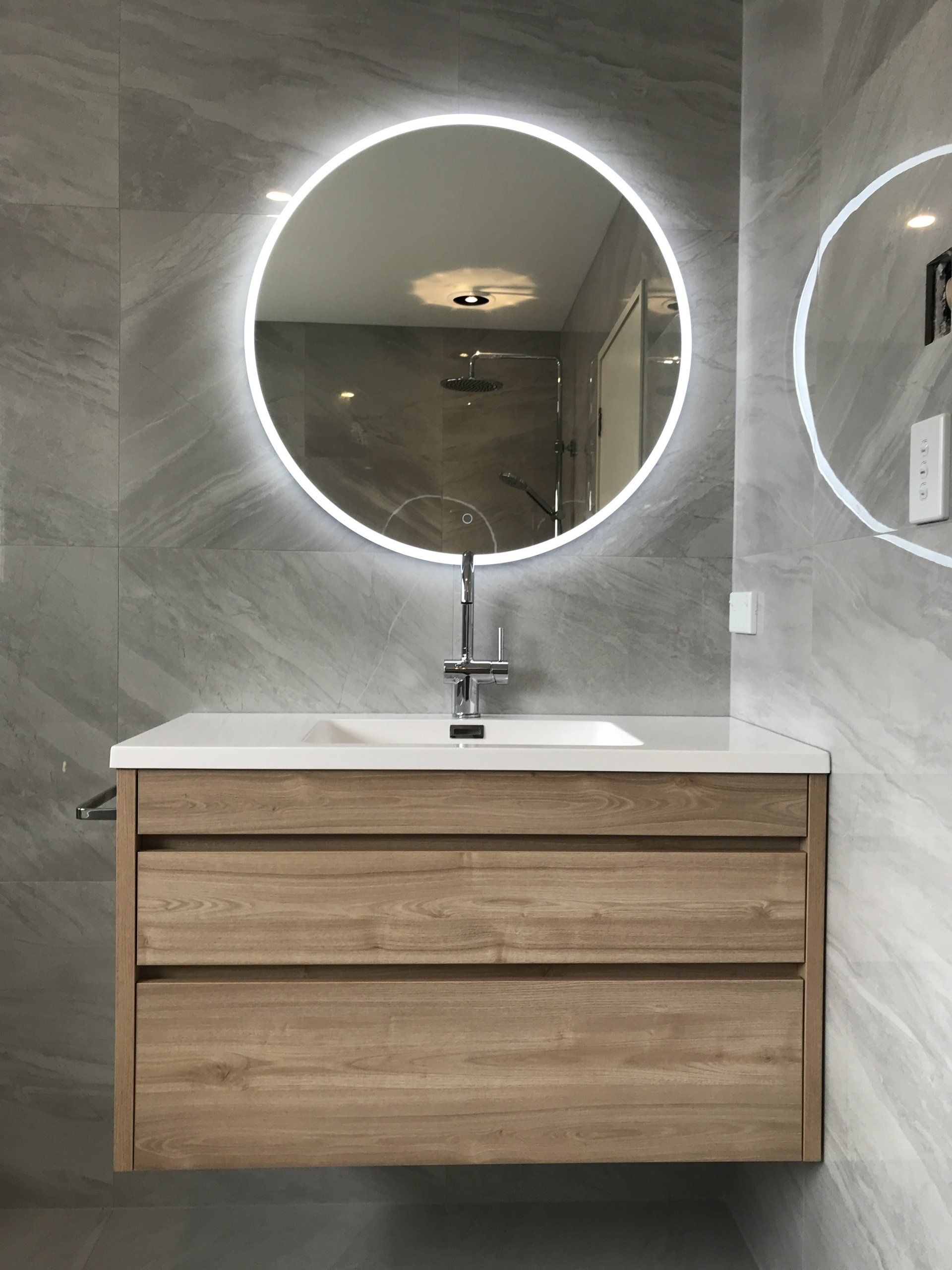 A bathroom with a sink and a round mirror
