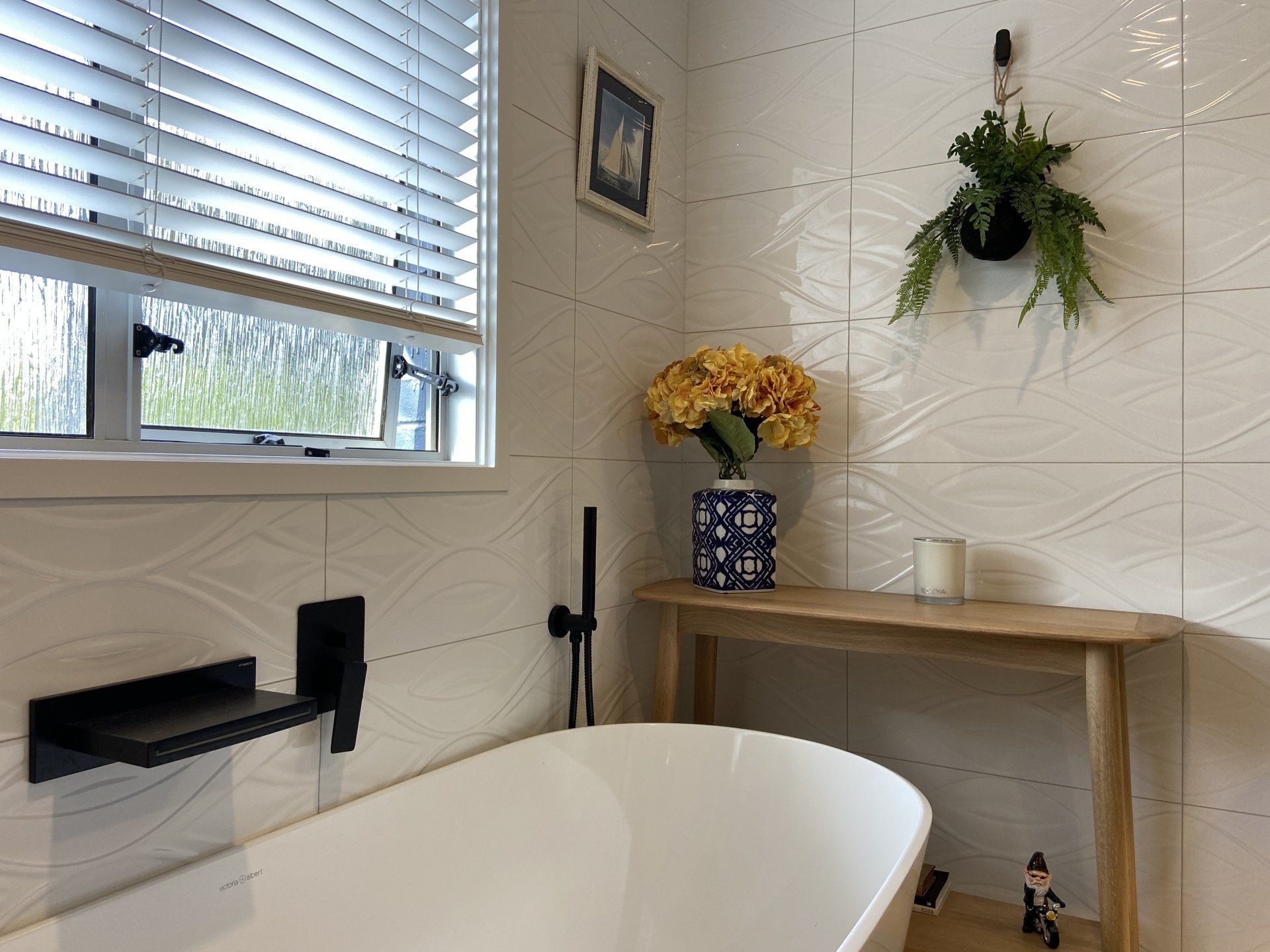 A bathroom with a tub and a window with blinds.