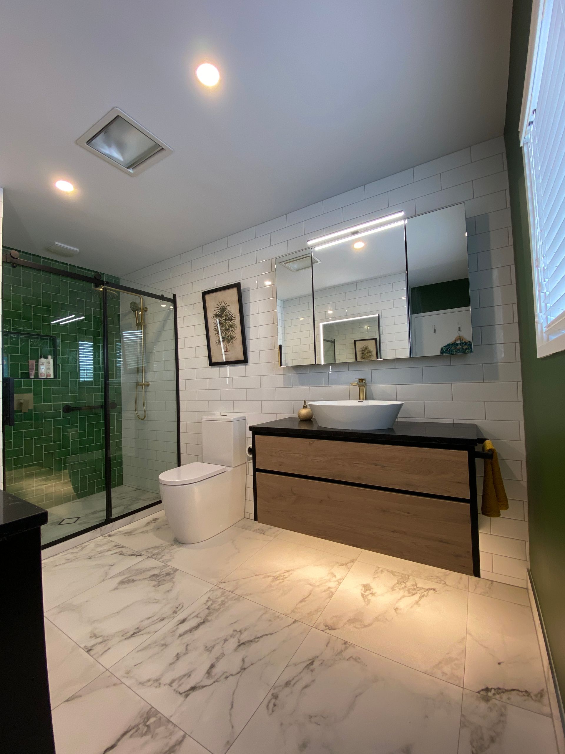 A bathroom with a toilet , sink , mirror and walk in shower.