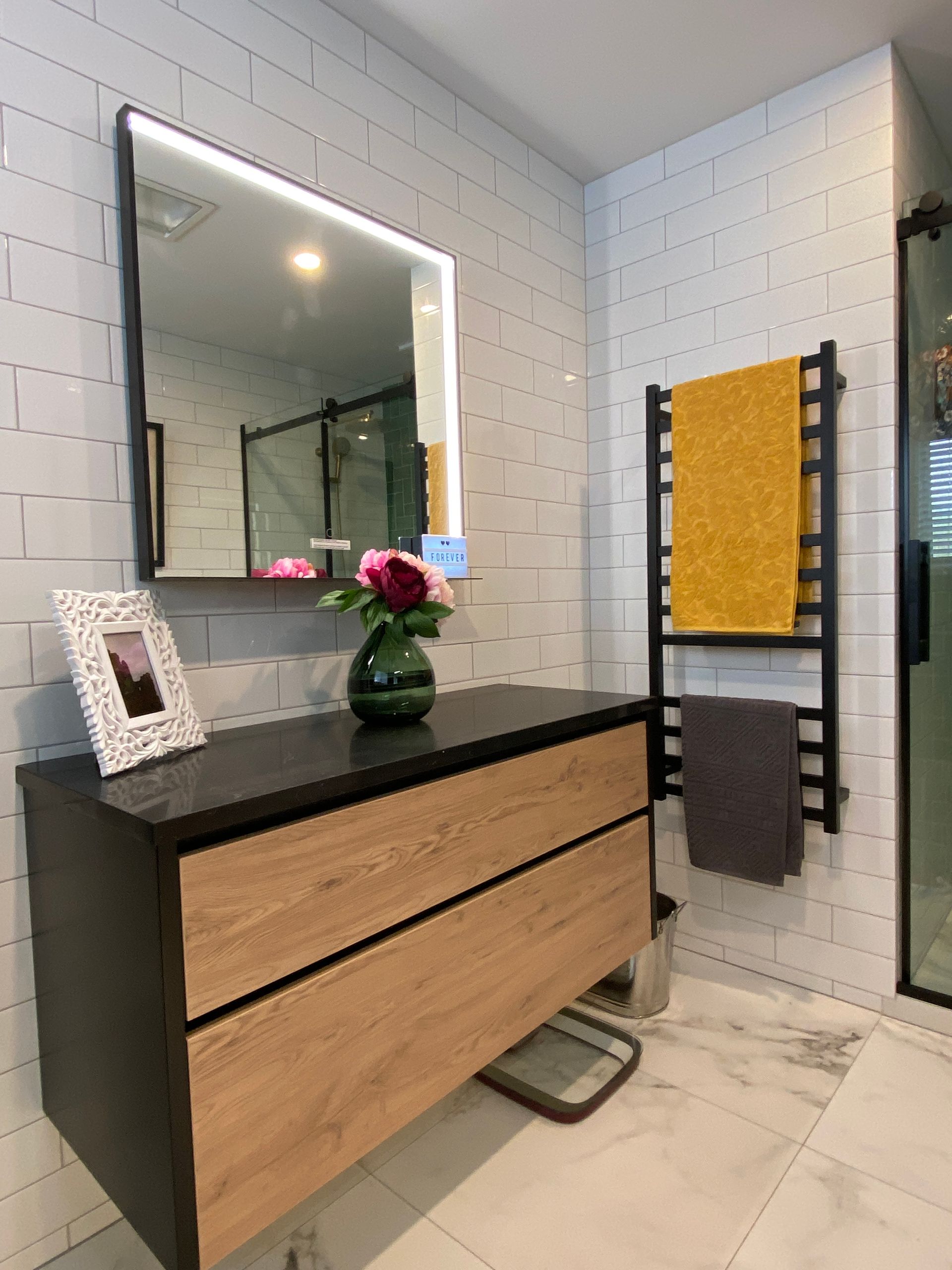 A bathroom with a vanity , mirror , and towel racks.