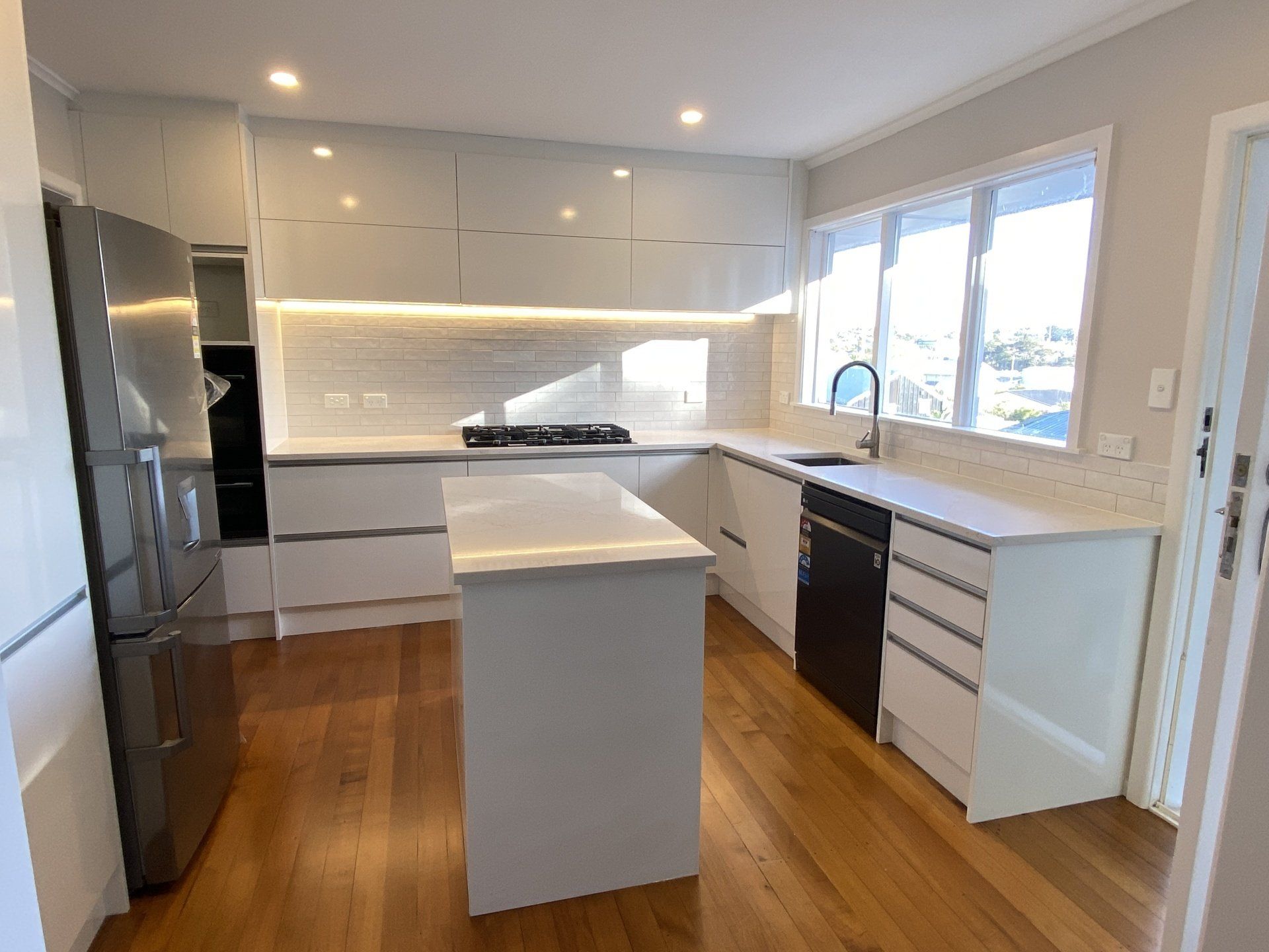 A kitchen with white cabinets , stainless steel appliances , and a large island.