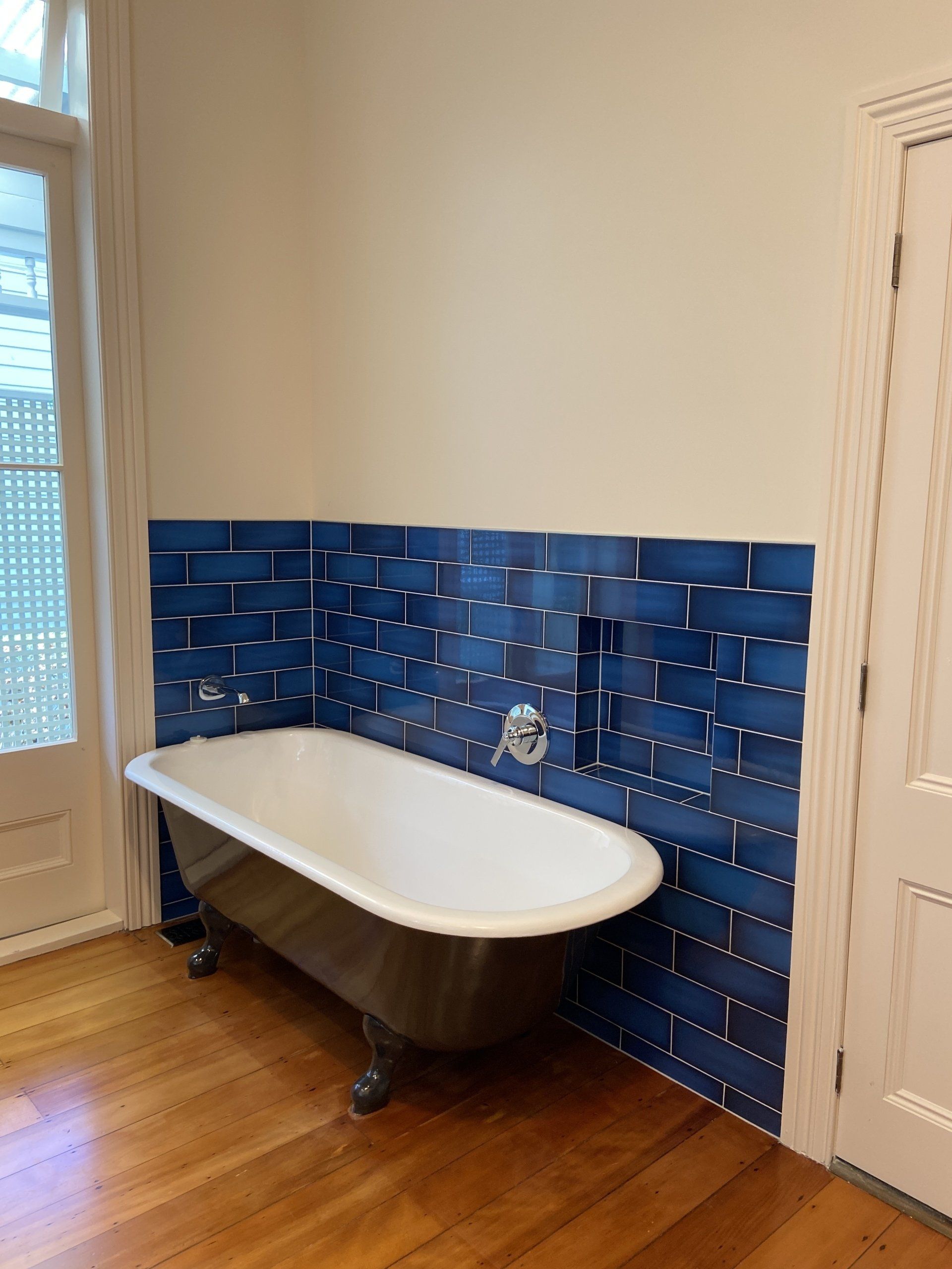A bathroom with a bathtub and blue tiles on the wall.