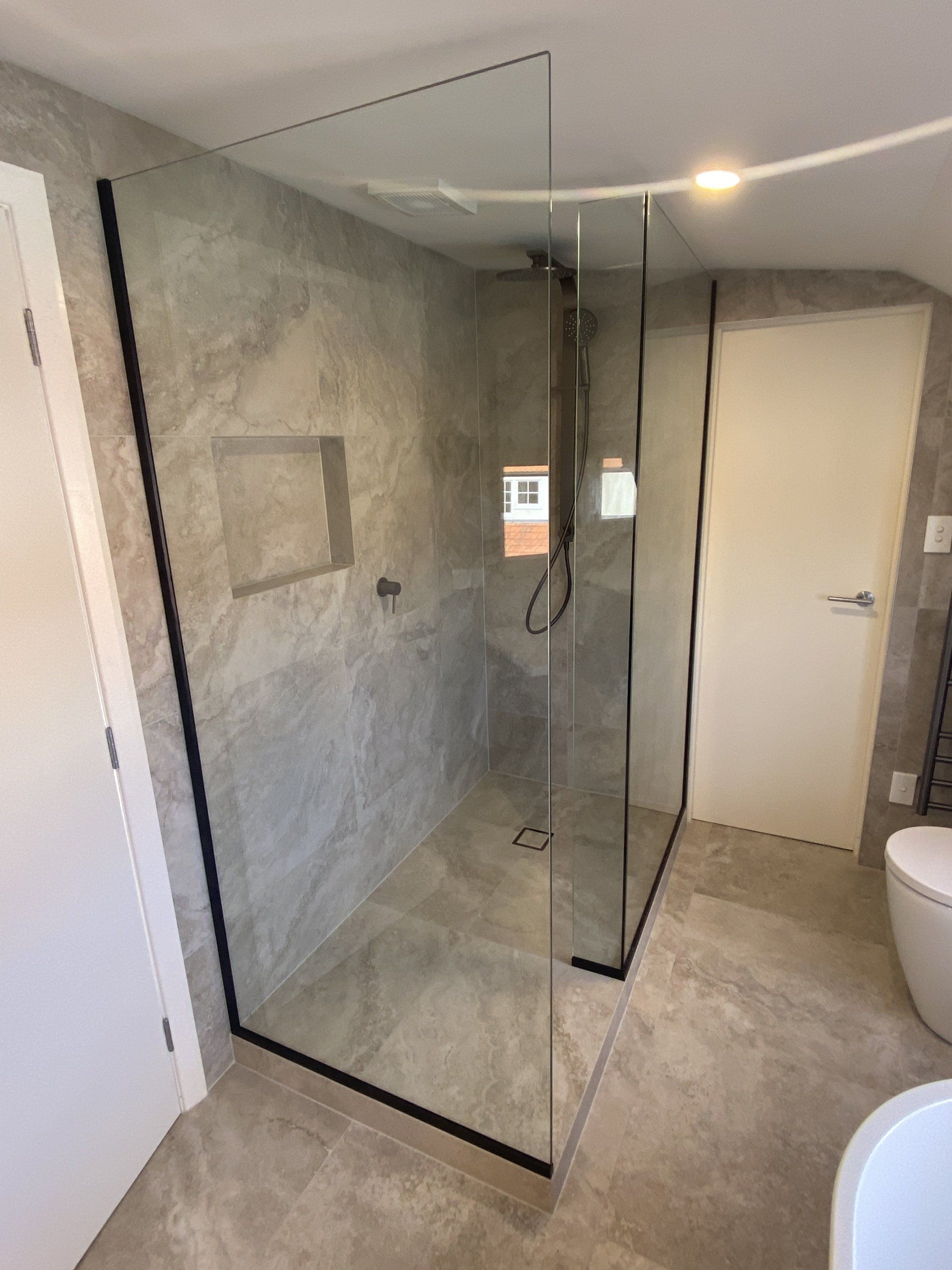 A bathroom with a walk in shower and a toilet.