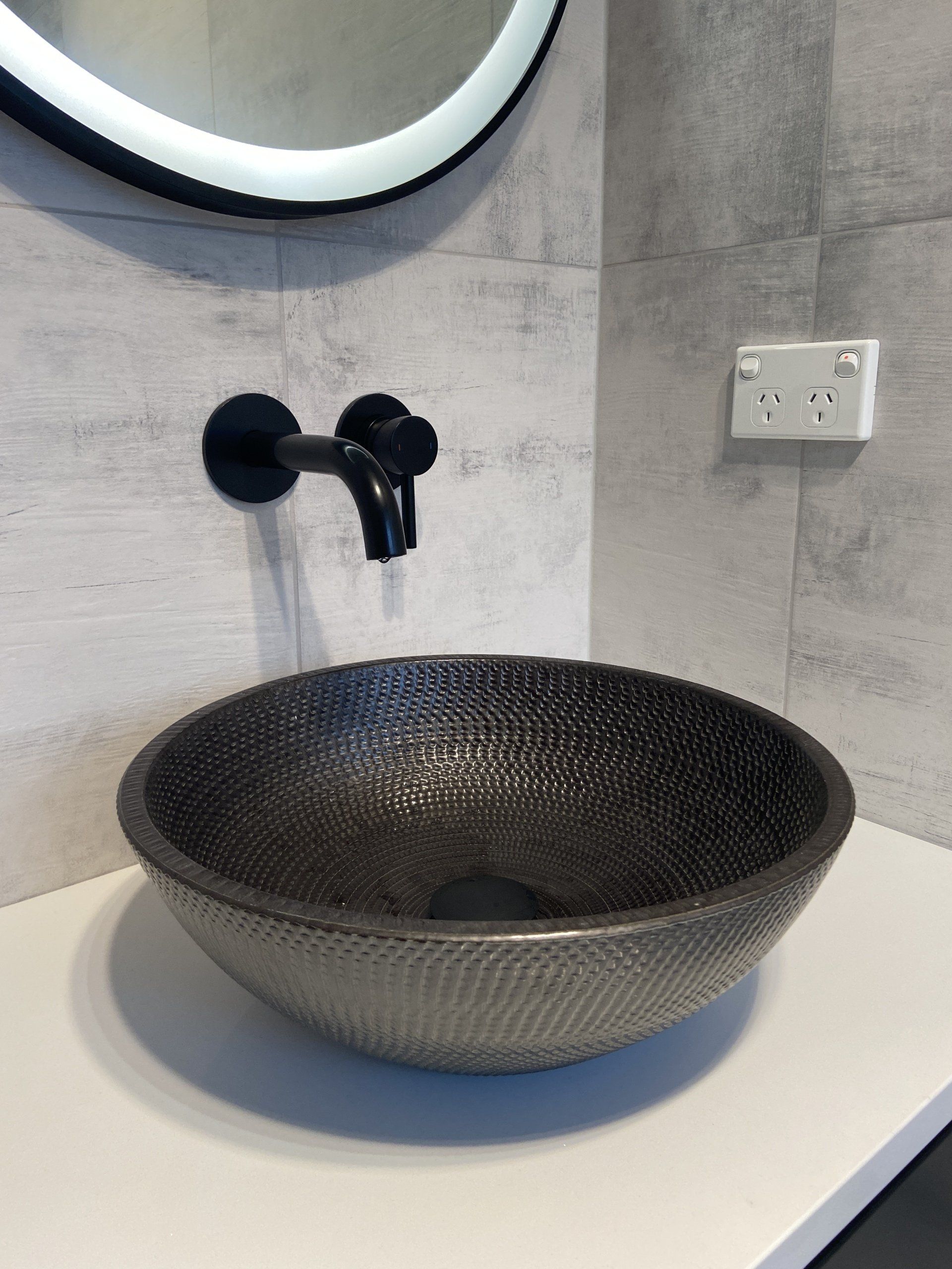 A bathroom sink with a black faucet and a mirror