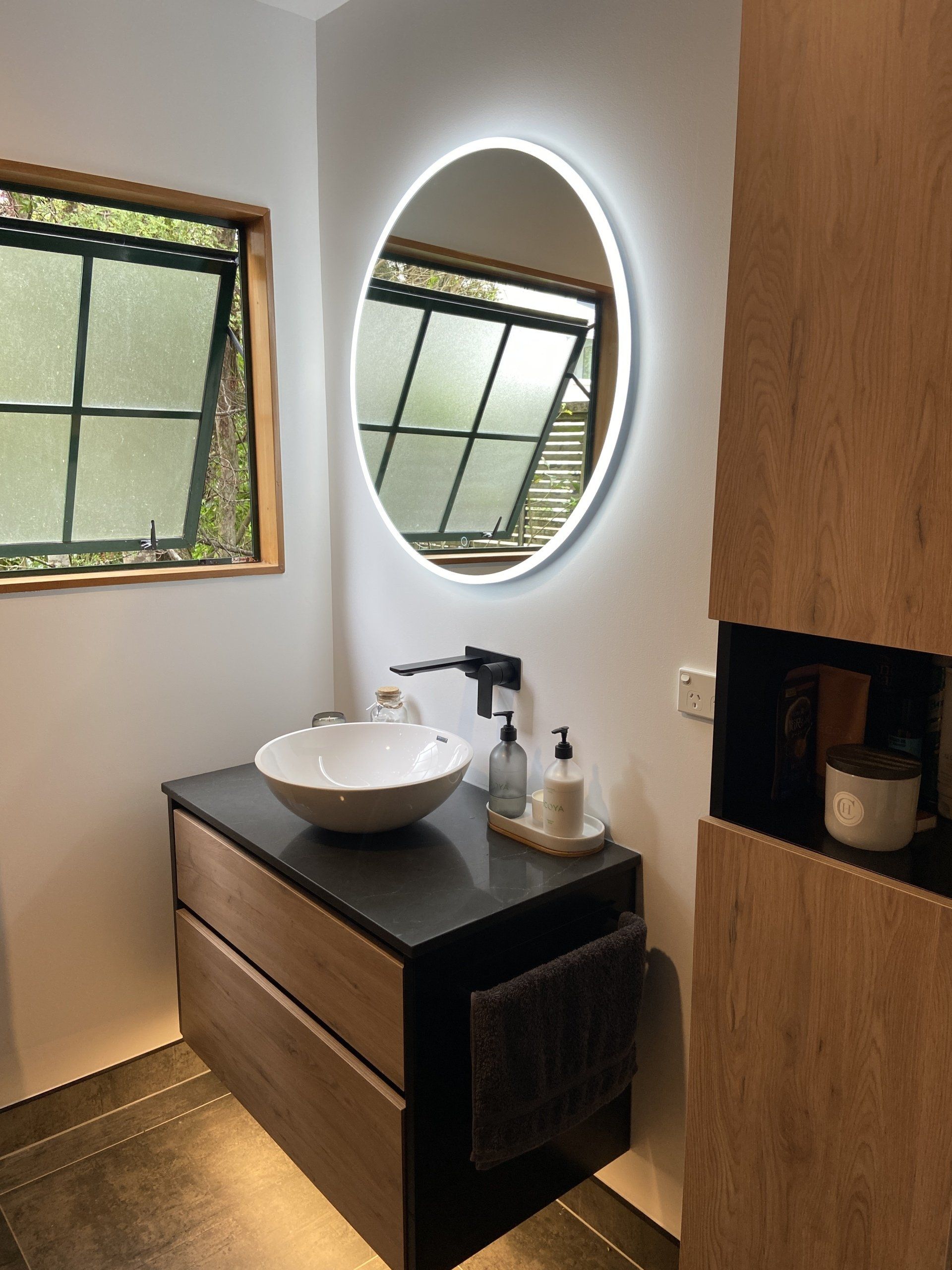 A bathroom with a sink and a round mirror