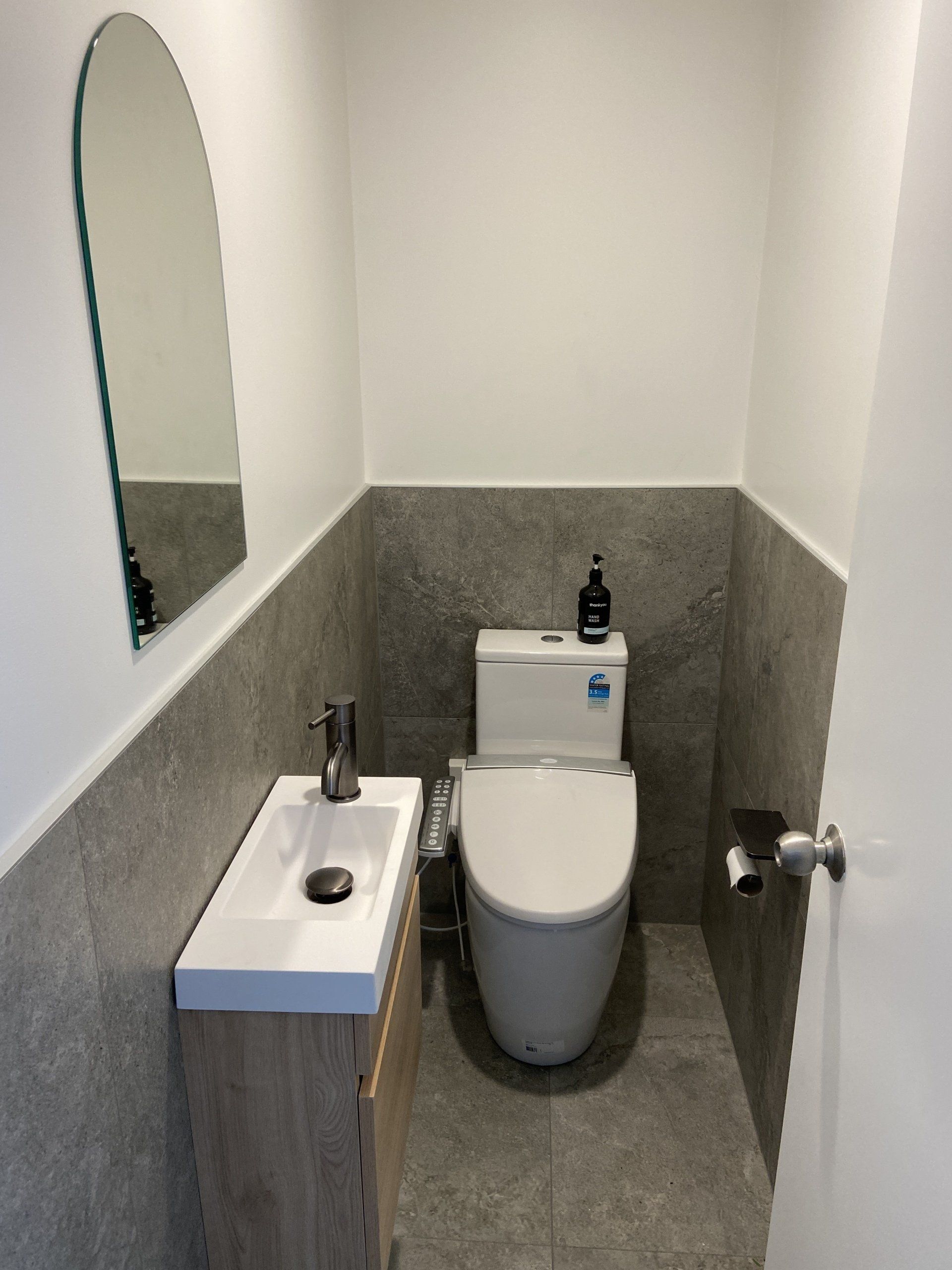 A bathroom with a toilet , sink and mirror