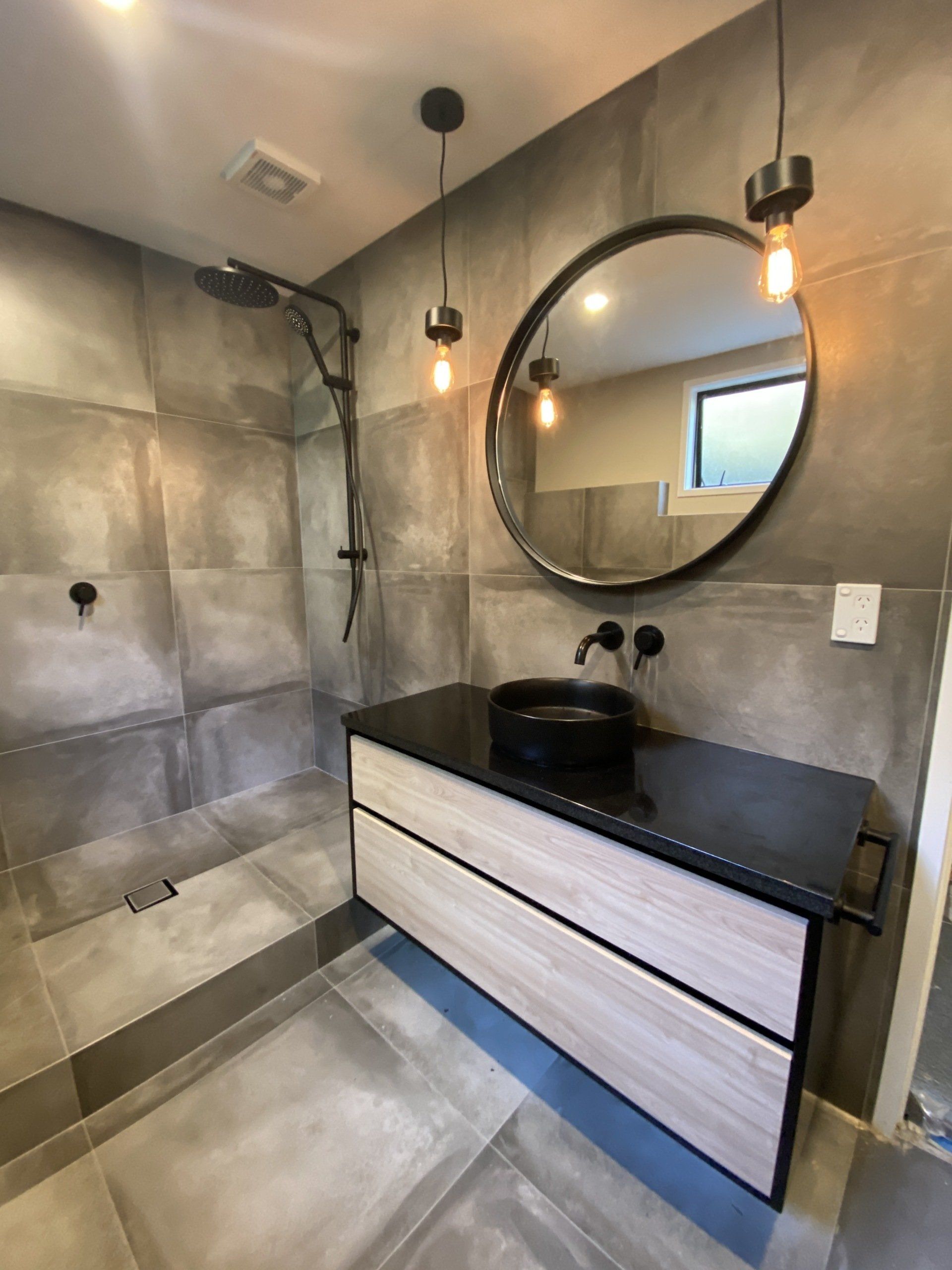 A bathroom with a sink , mirror and shower.