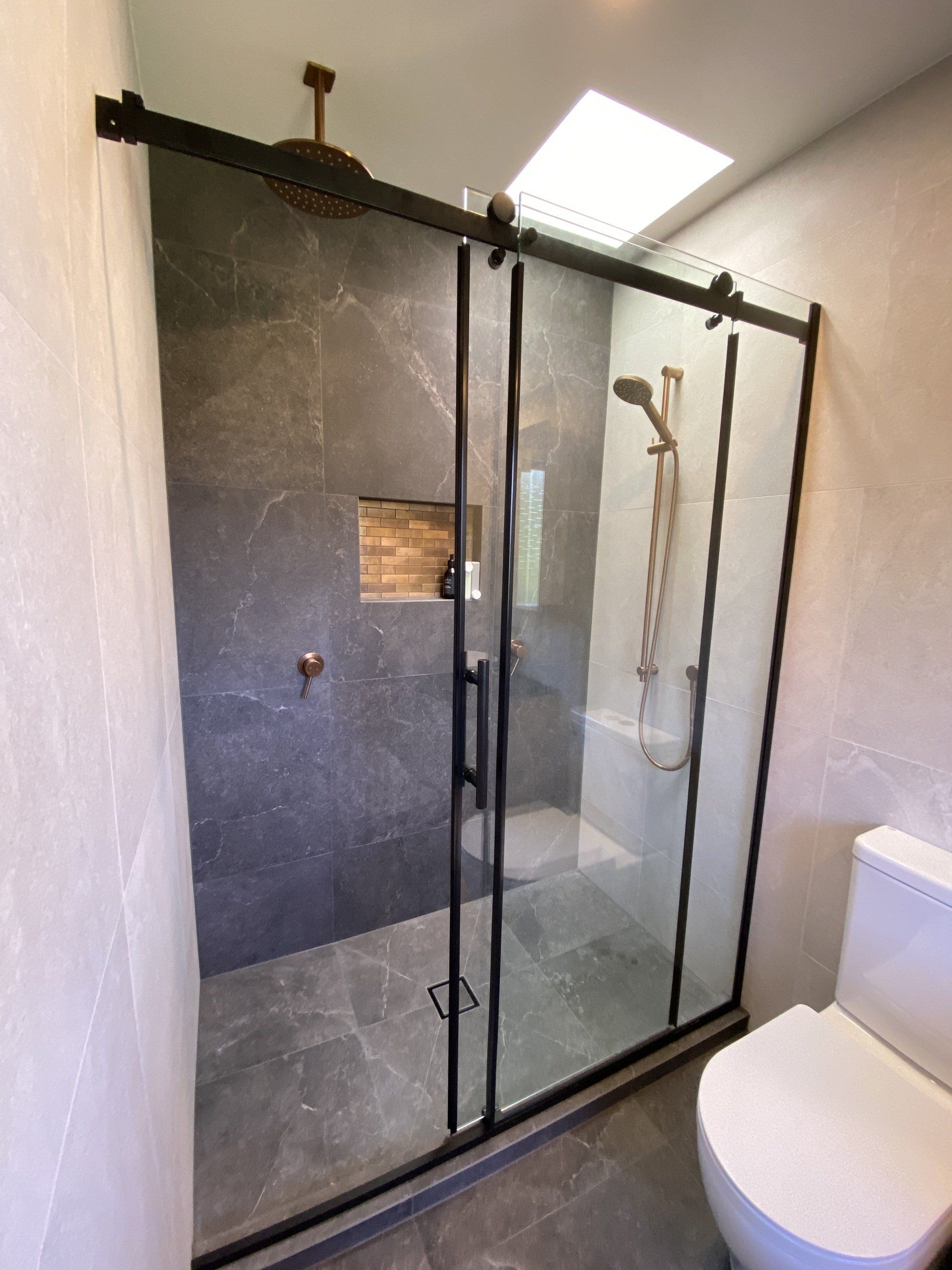 A bathroom with a toilet and a shower with sliding glass doors.