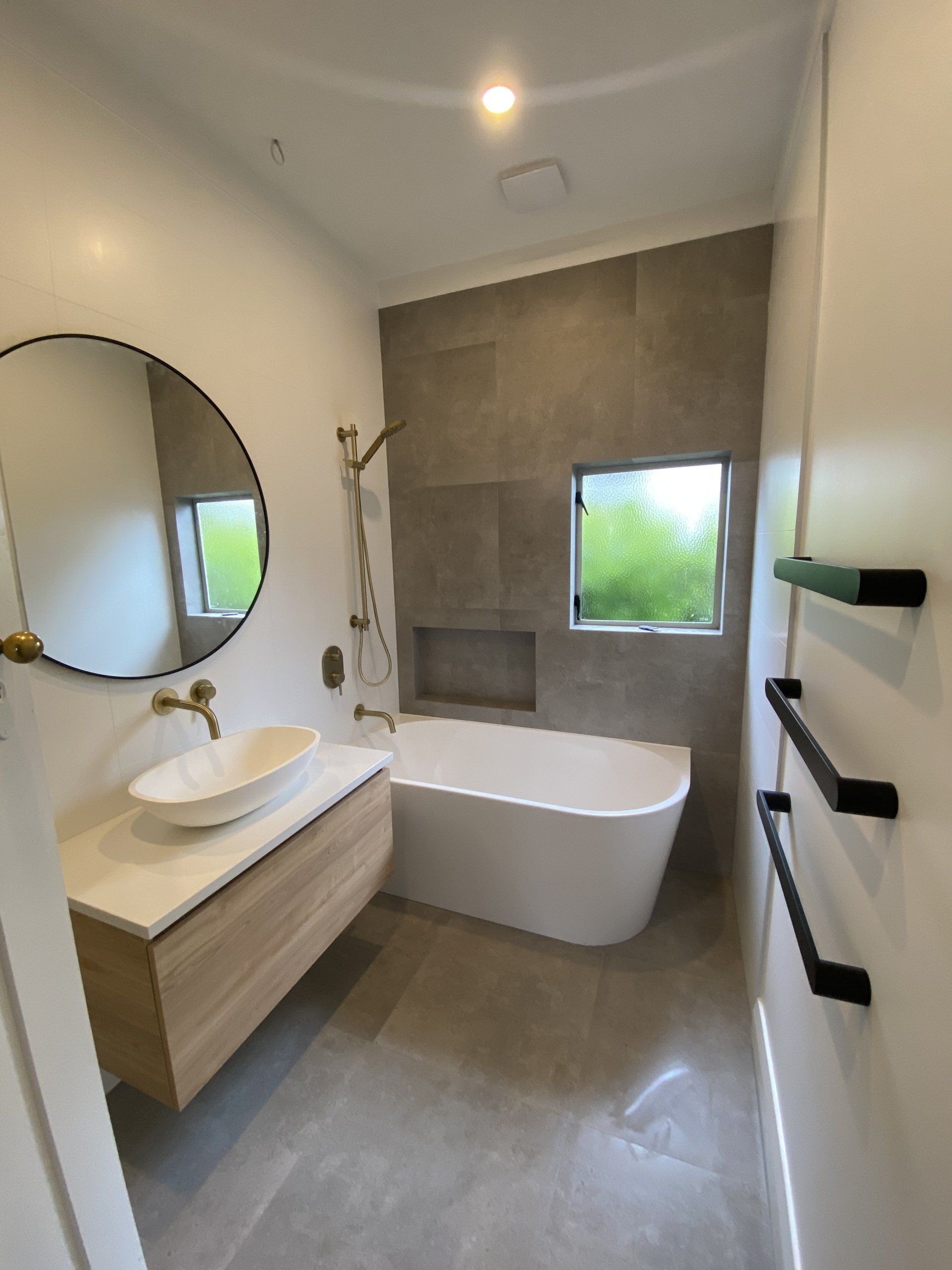 A bathroom with a bathtub , sink , mirror and window.