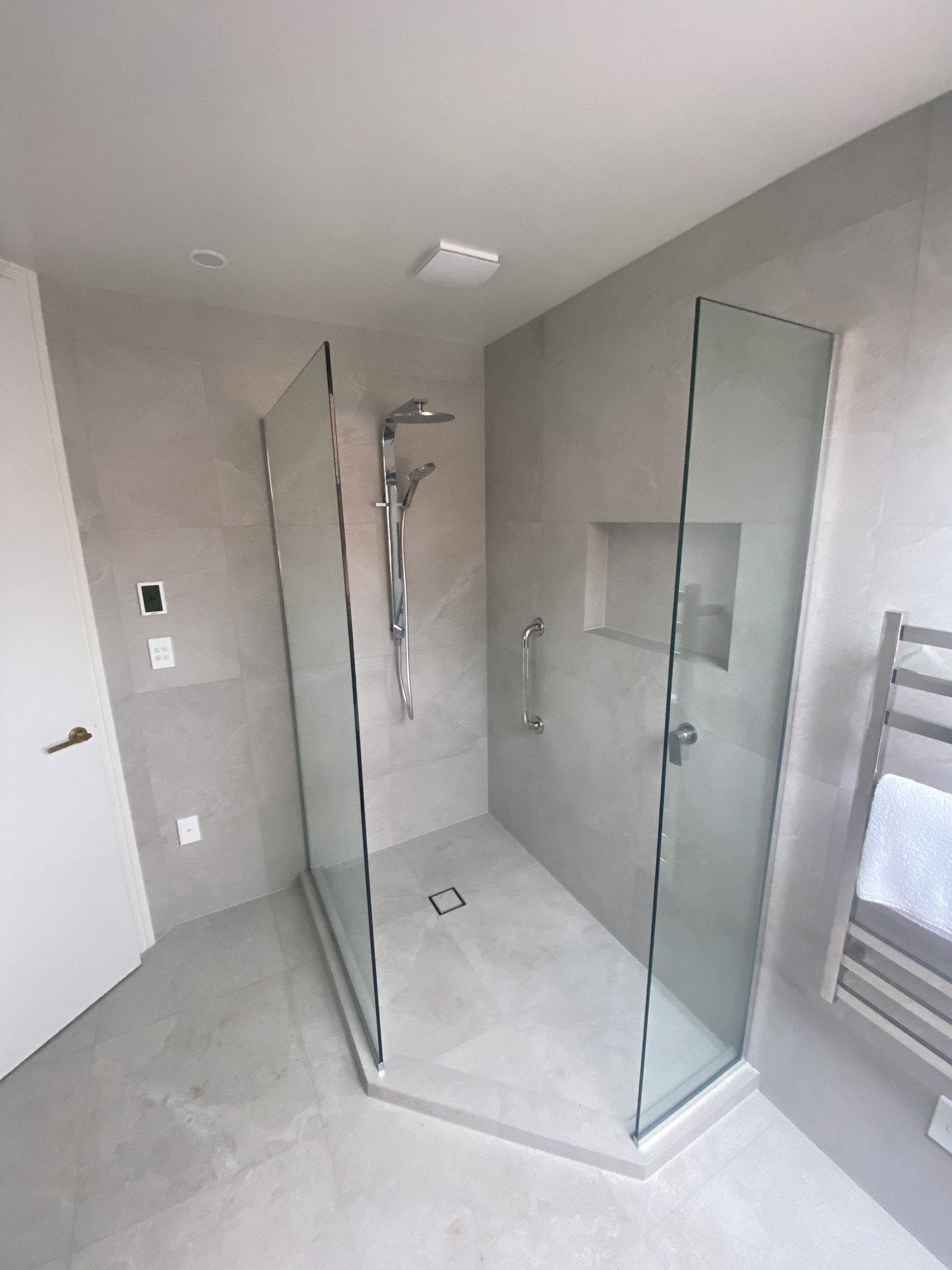 A bathroom with a walk in shower and a towel rack