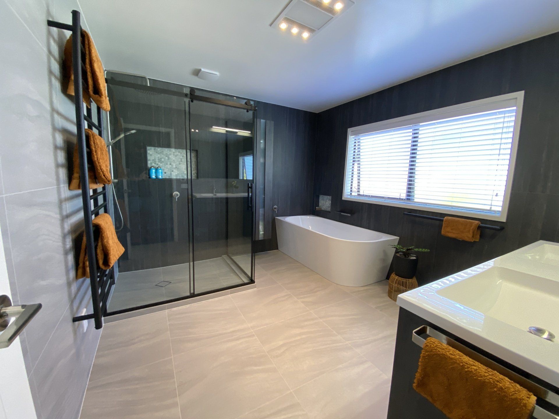 A bathroom with a tub , sink , shower and window.