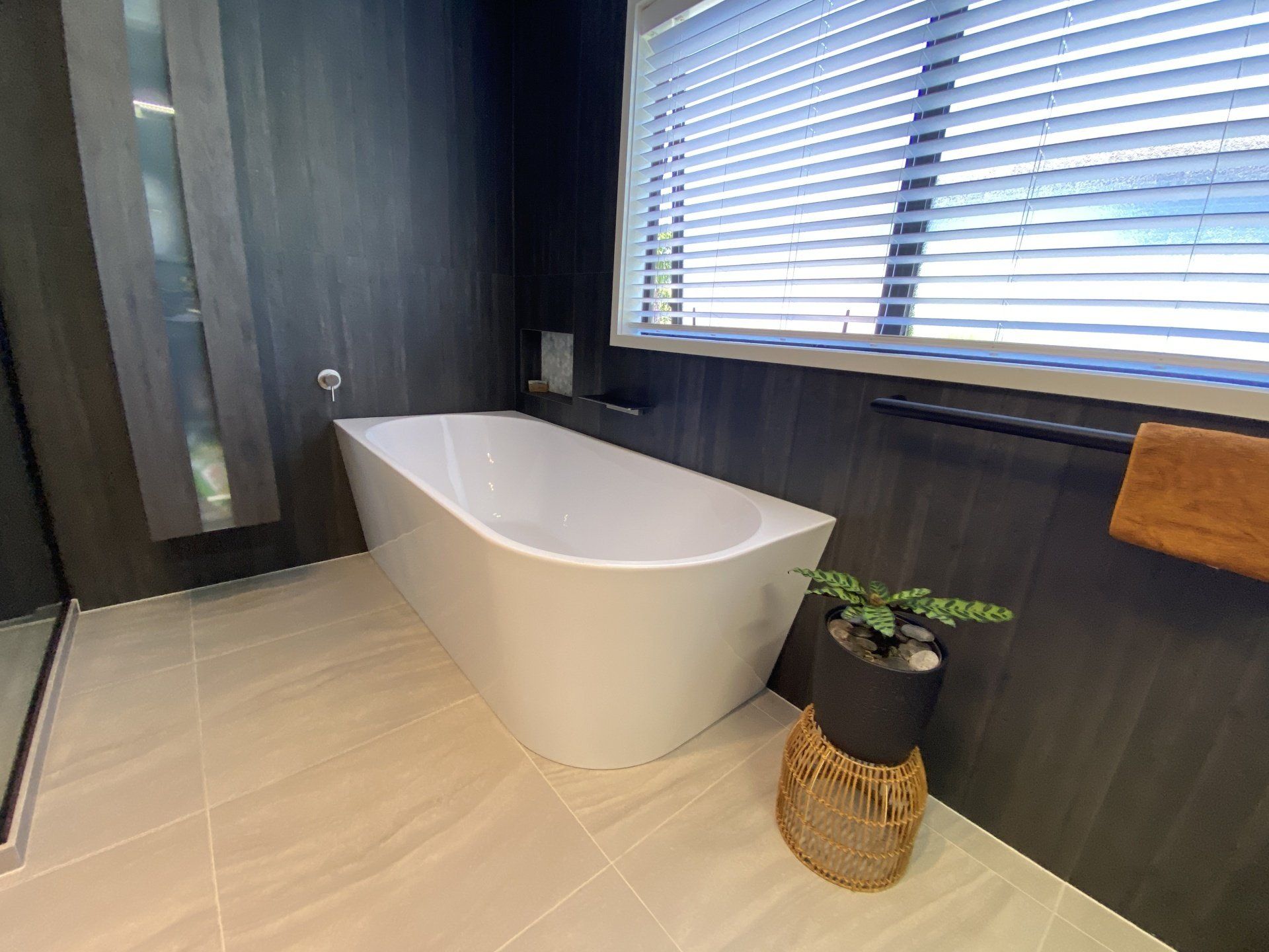 A bathroom with a bathtub and a window with blinds.