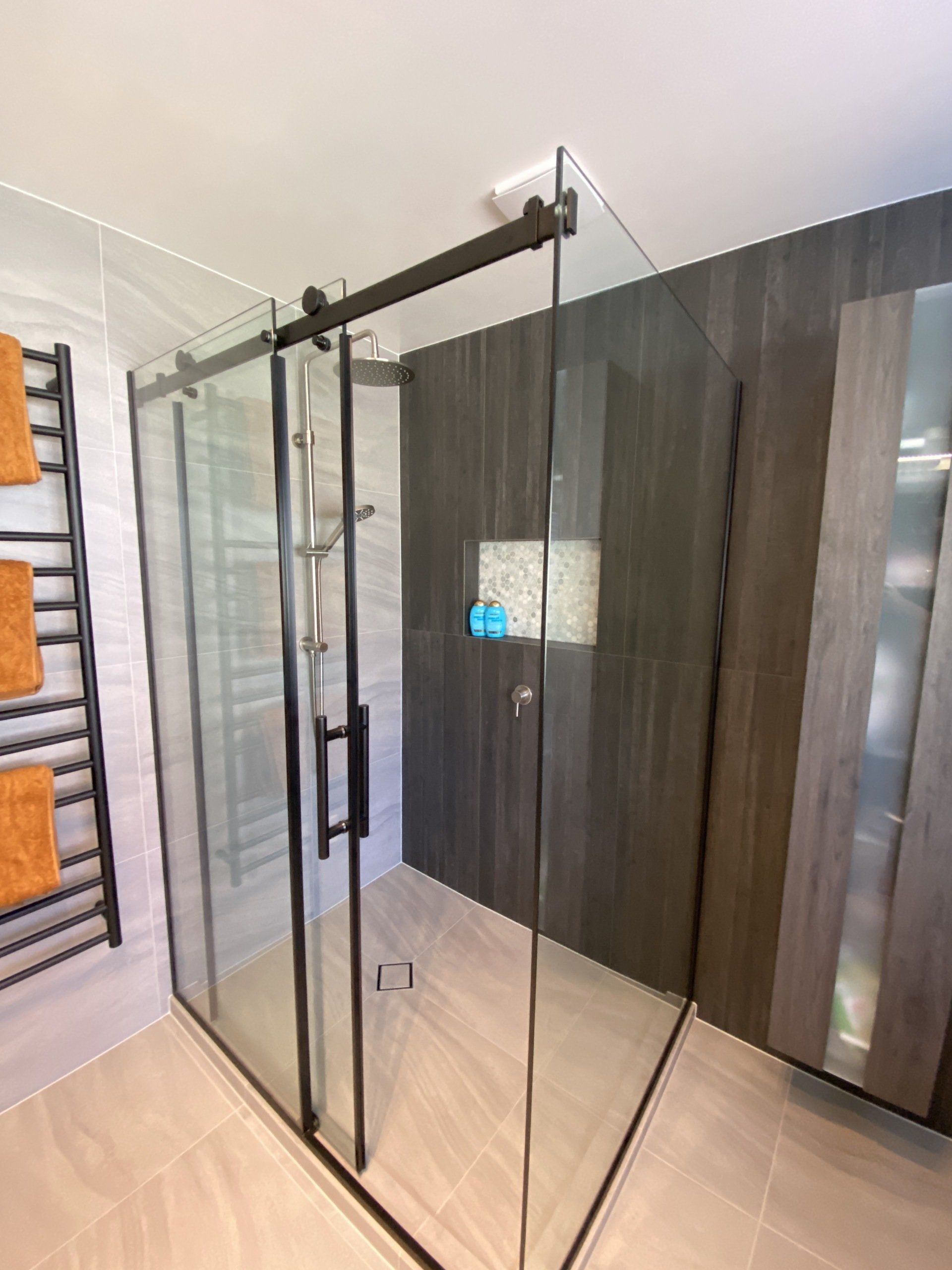A bathroom with a sliding glass shower door and a towel rack.