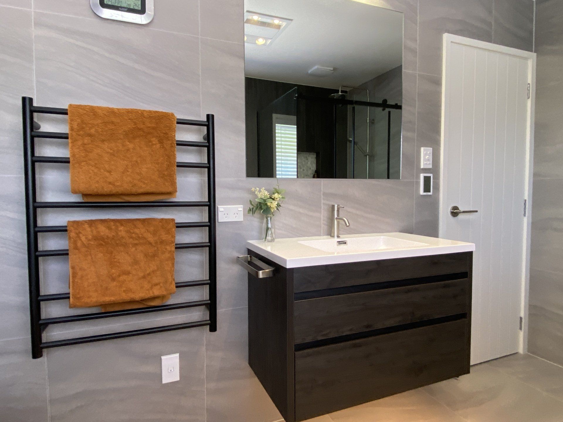A bathroom with a sink , mirror and towel racks.