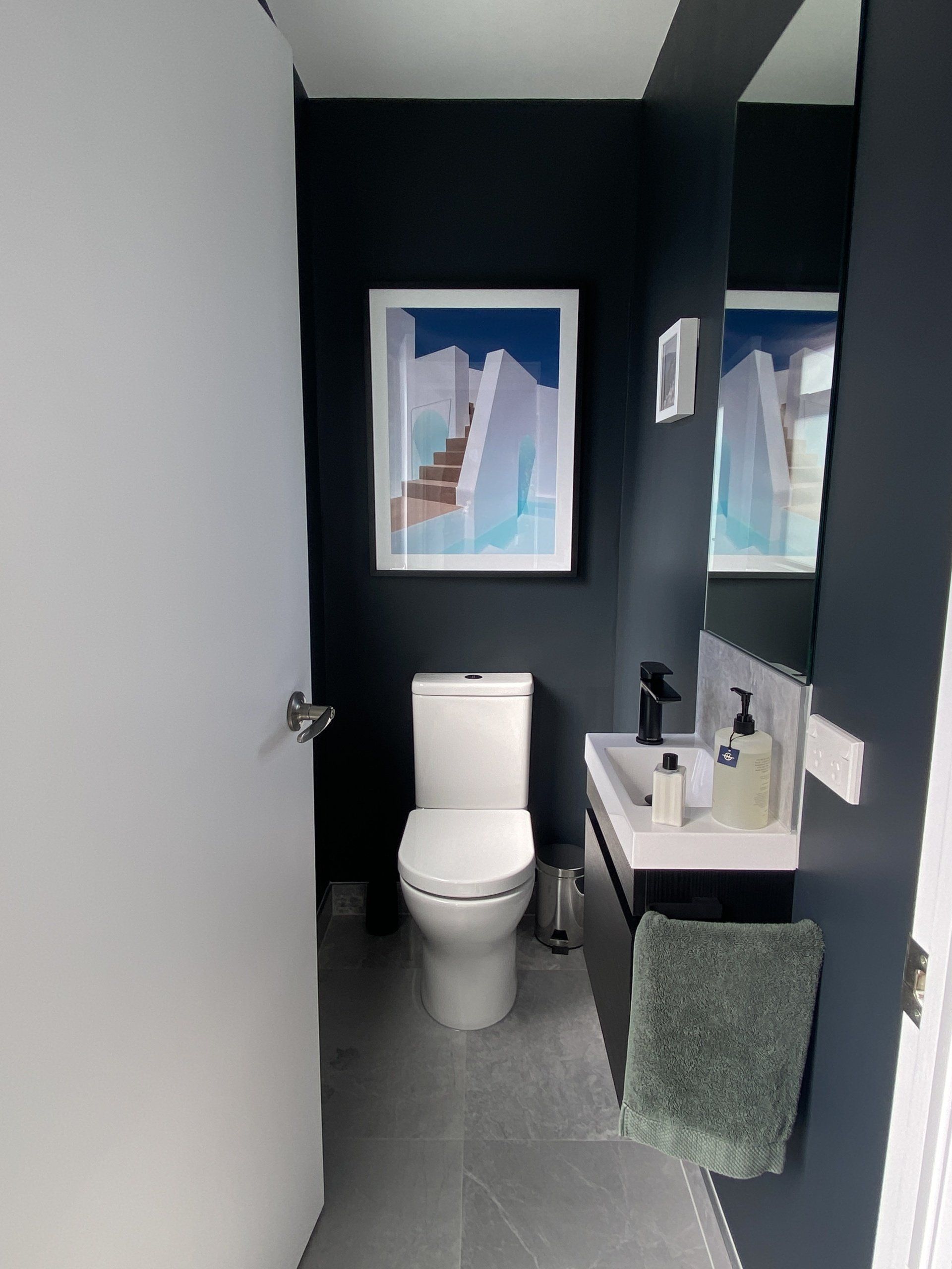 A bathroom with a toilet , sink and mirror.