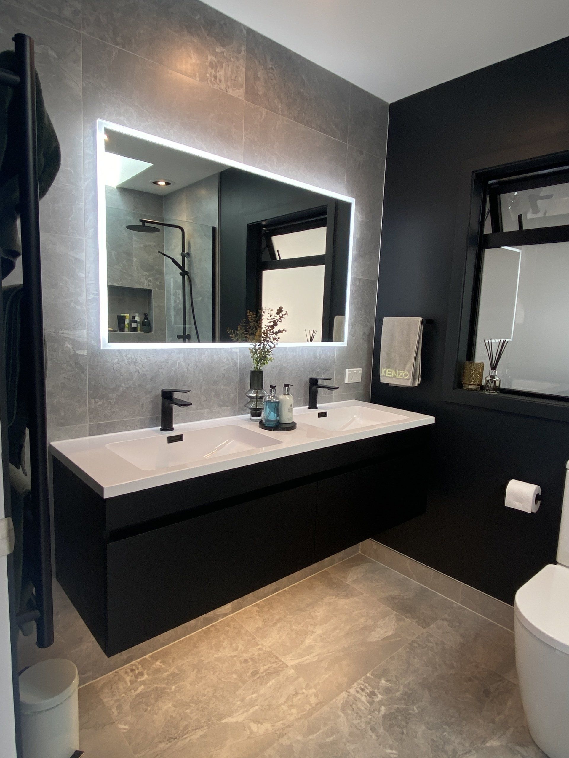 A bathroom with two sinks , a toilet , and a large mirror.