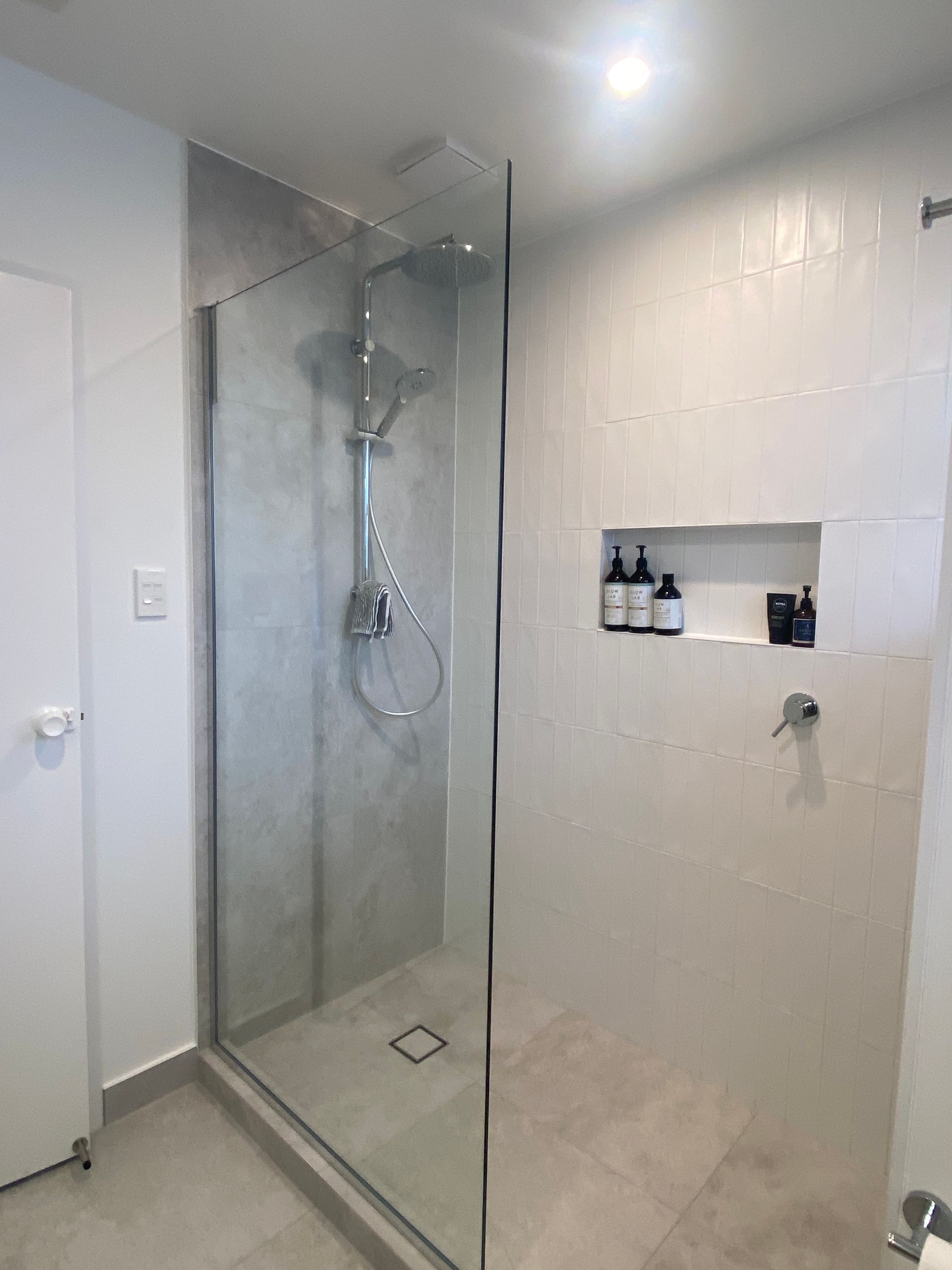 A bathroom with a walk in shower with a glass door.