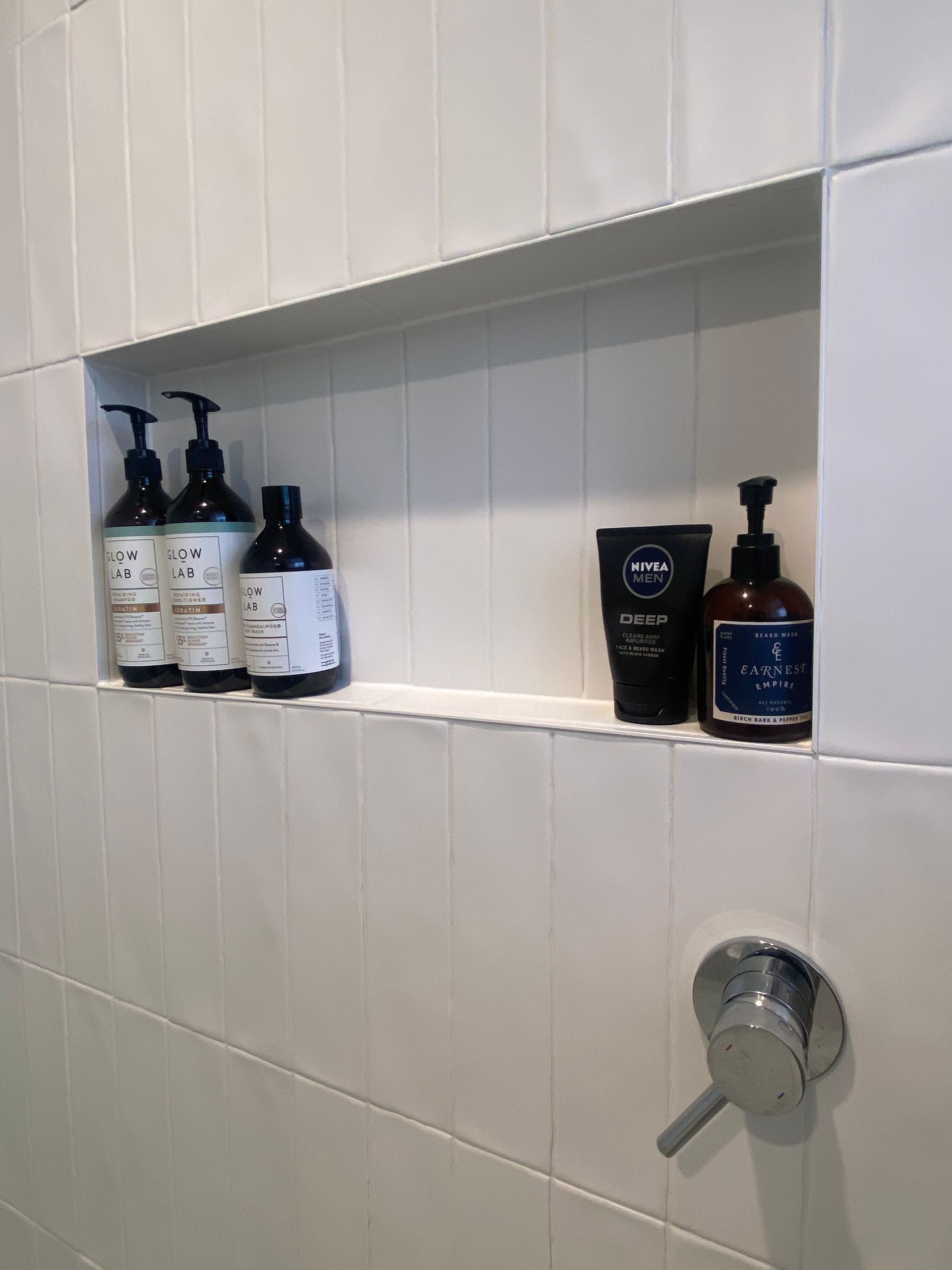 A bathroom with a shelf filled with bottles of soap and lotion.