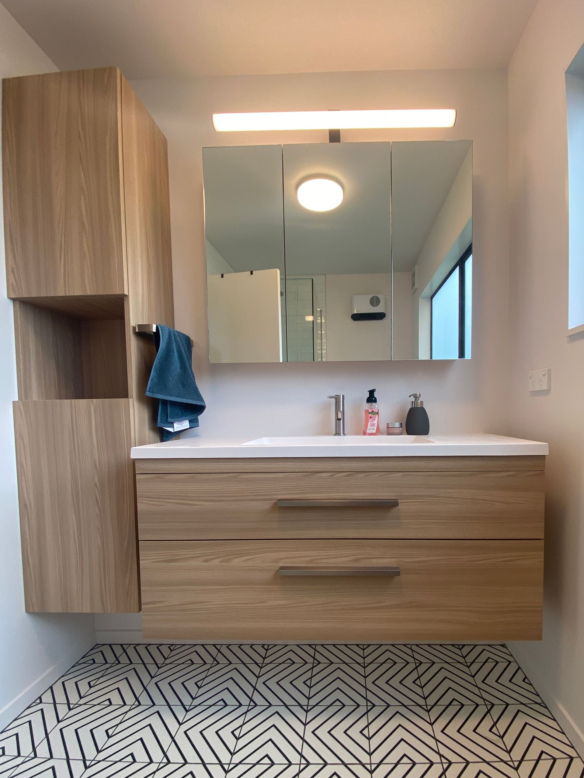 Stylish bathroom countertop with tall storage tower in a small Auckland bathroom
