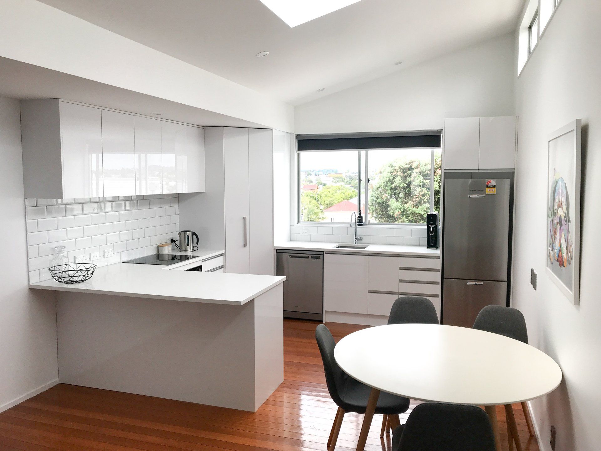 A kitchen with white cabinets , a table and chairs.
