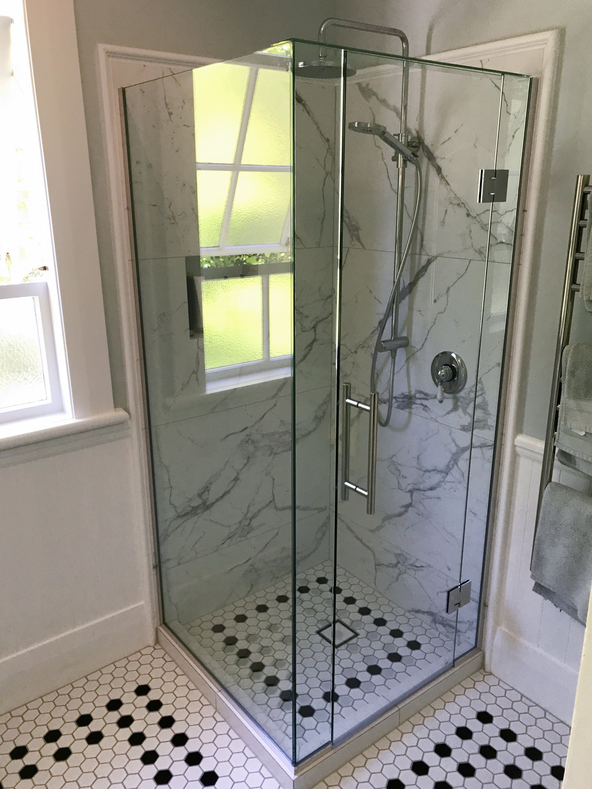 A bathroom with a shower stall and a window.