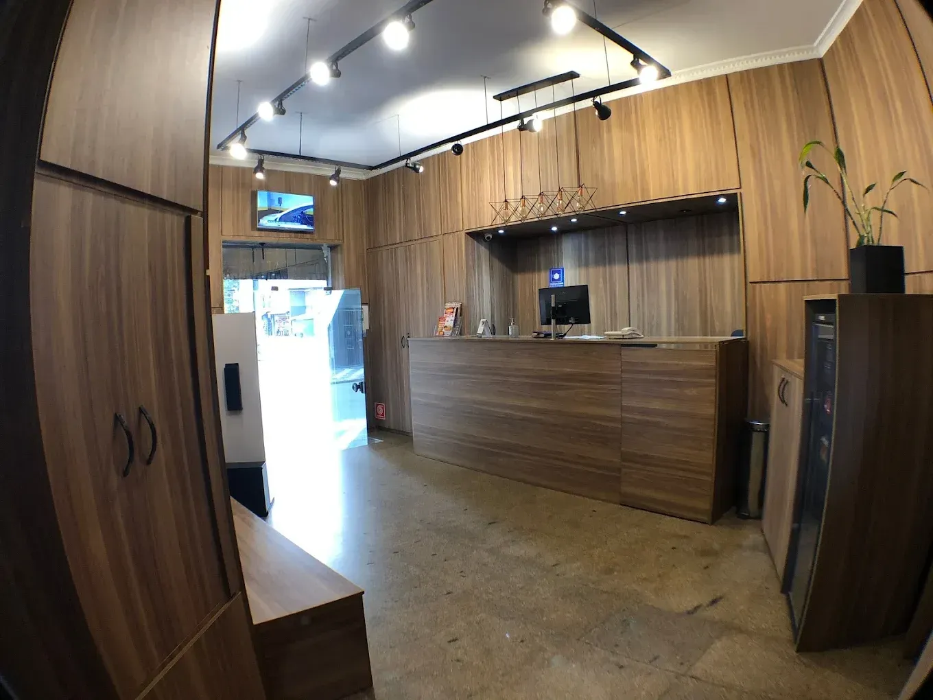 Interior de uma recepção com paredes e móveis de madeira. Balcão de recepção no centro.