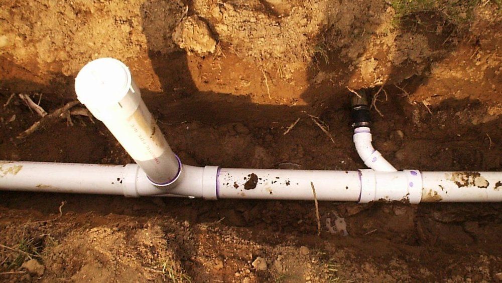 A white pipe is laying in the dirt.