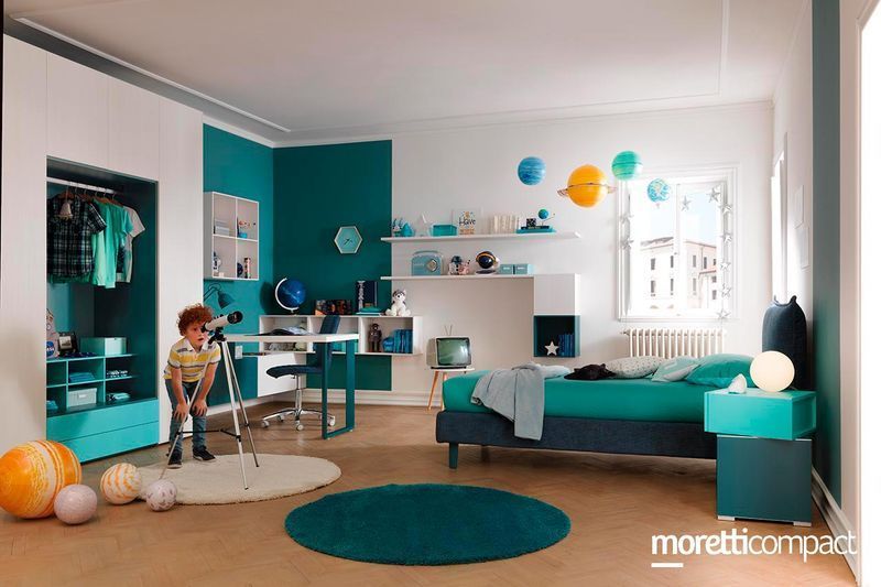 Soggiorno moderno con divano color verde acqua, angolo scrivania, palloncini e un bambino vicino a una piccola bicicletta.
