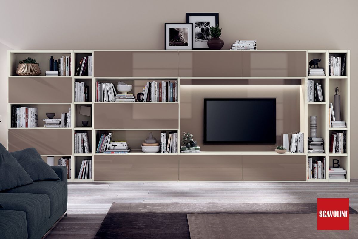 Soggiorno moderno con mobile TV a parete, televisore, mensole, libri e complementi d'arredo in tonalità neutre di legno.