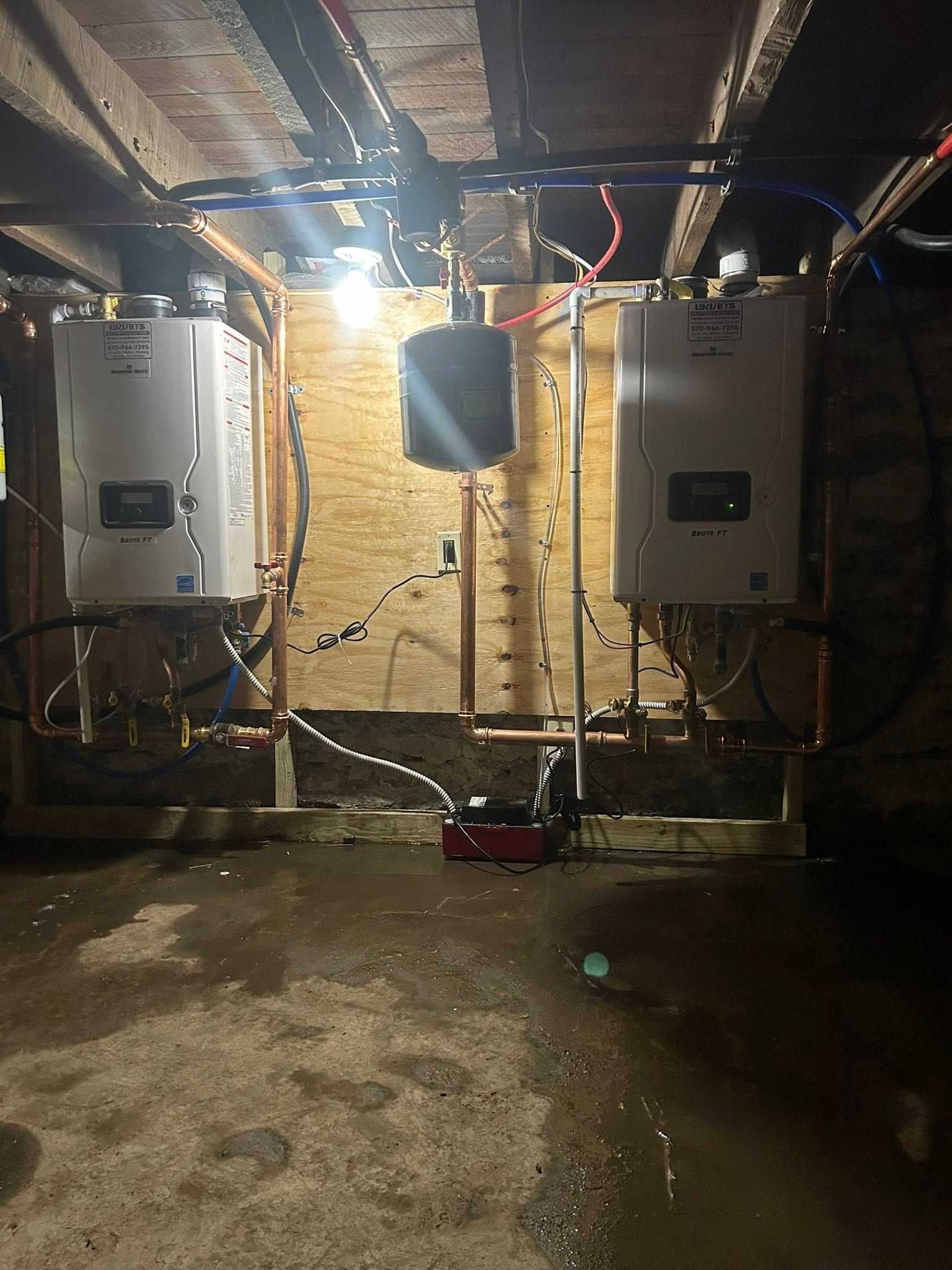 Two white water heaters with pipes and wiring in a basement setting.