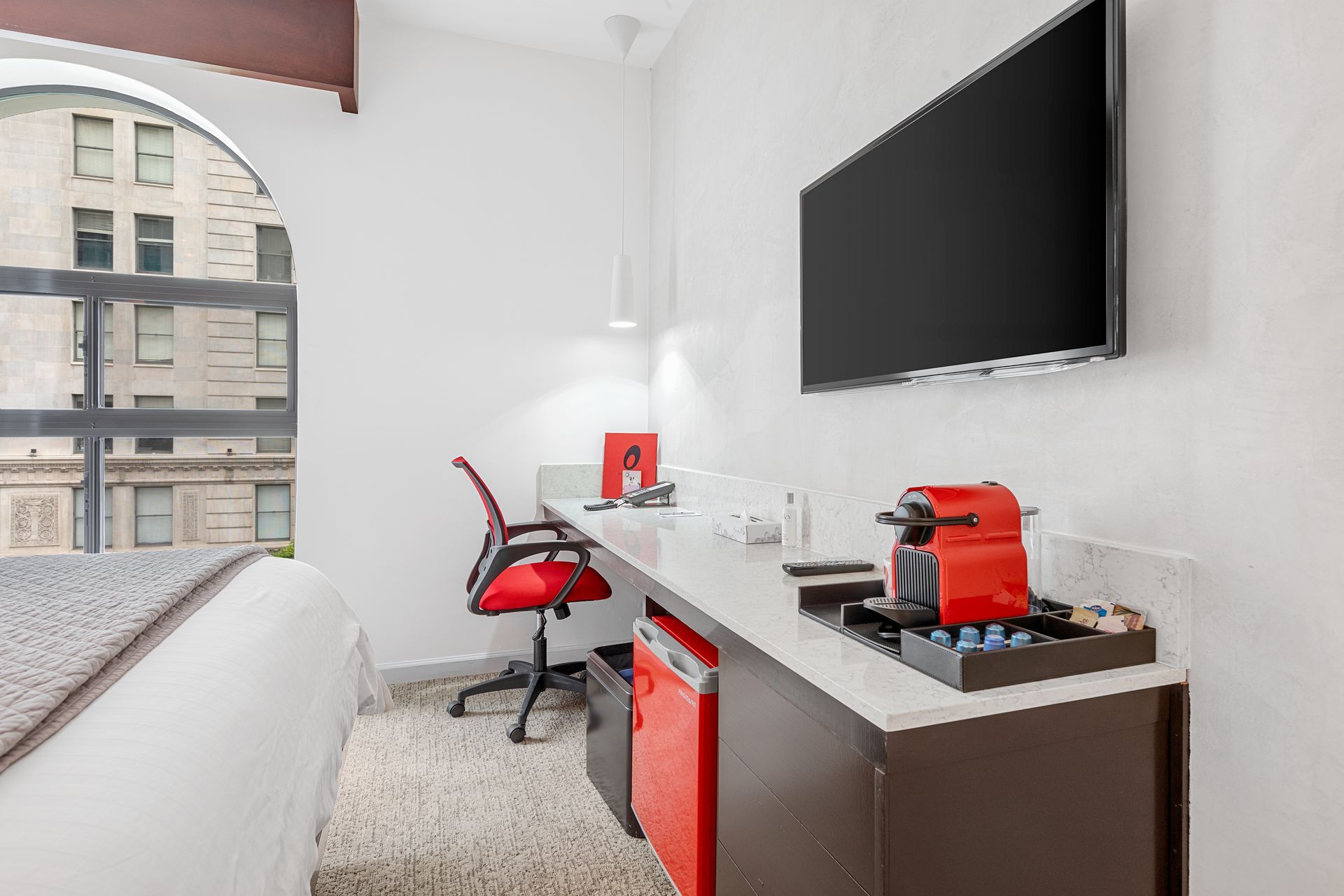 A hotel room with a bed , desk , chair and television.