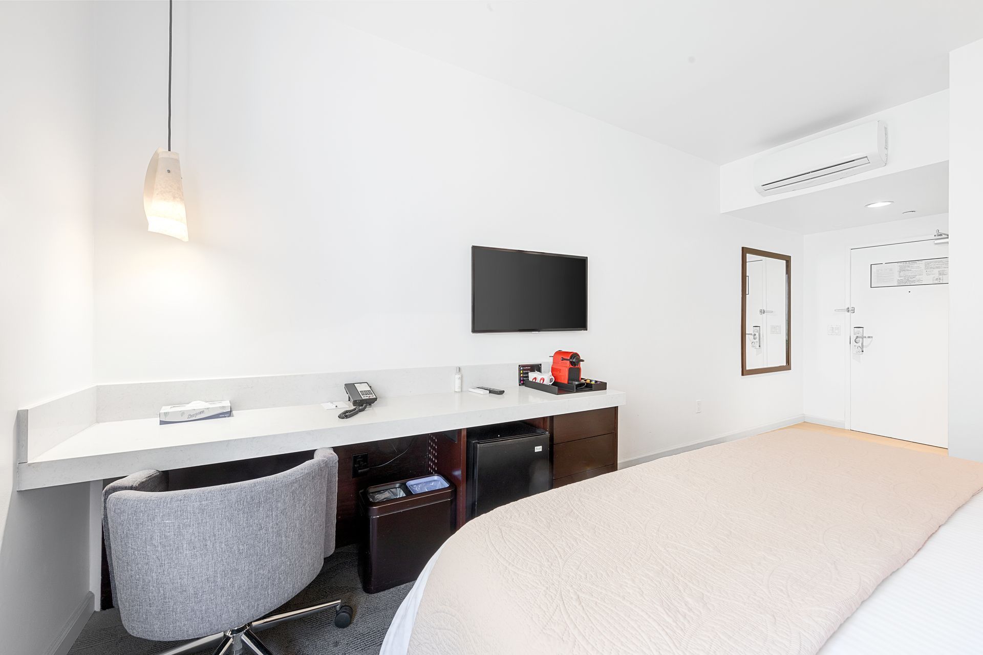 A hotel room with a bed , desk , chair and television.