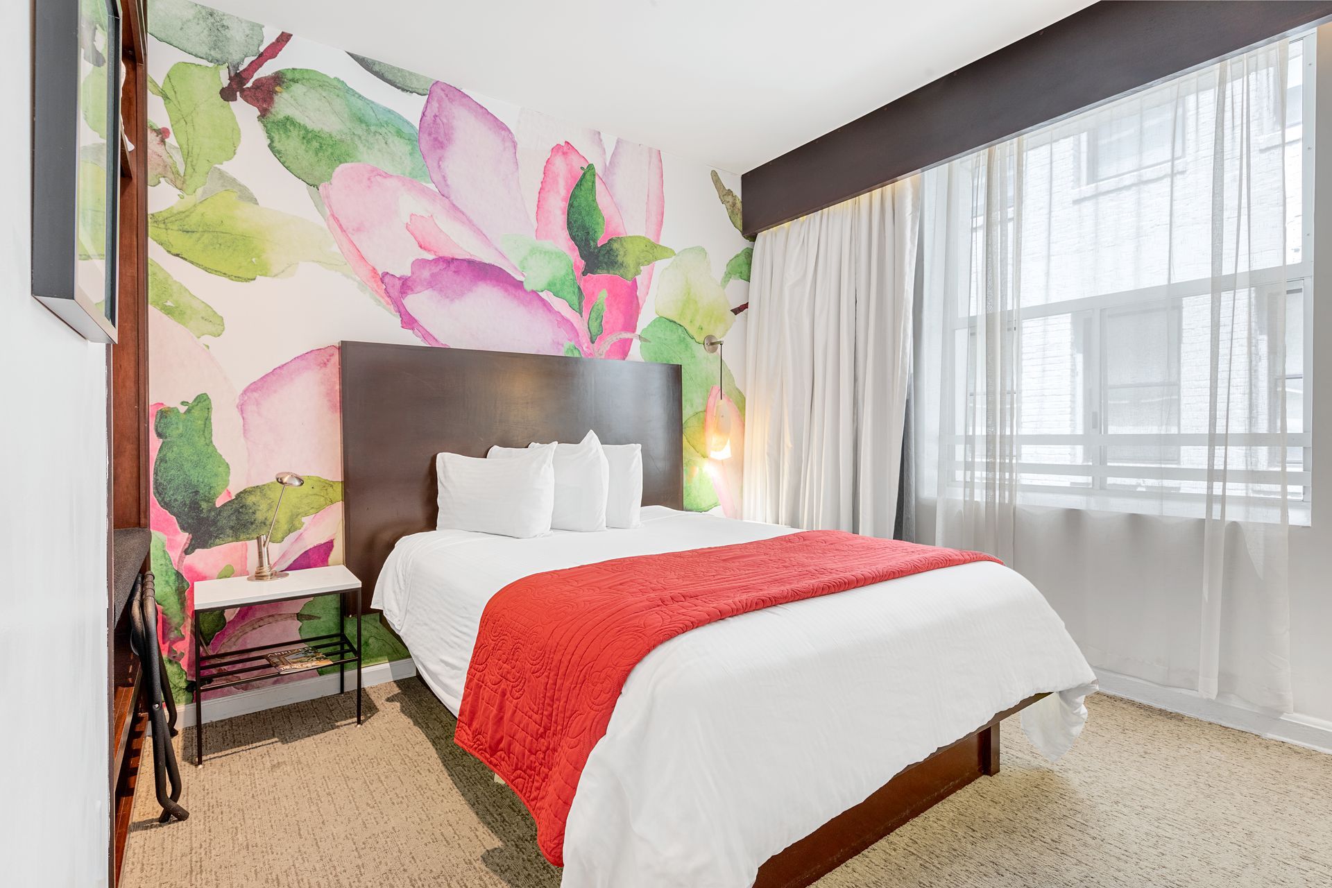 A hotel room with a bed and a mural on the wall.