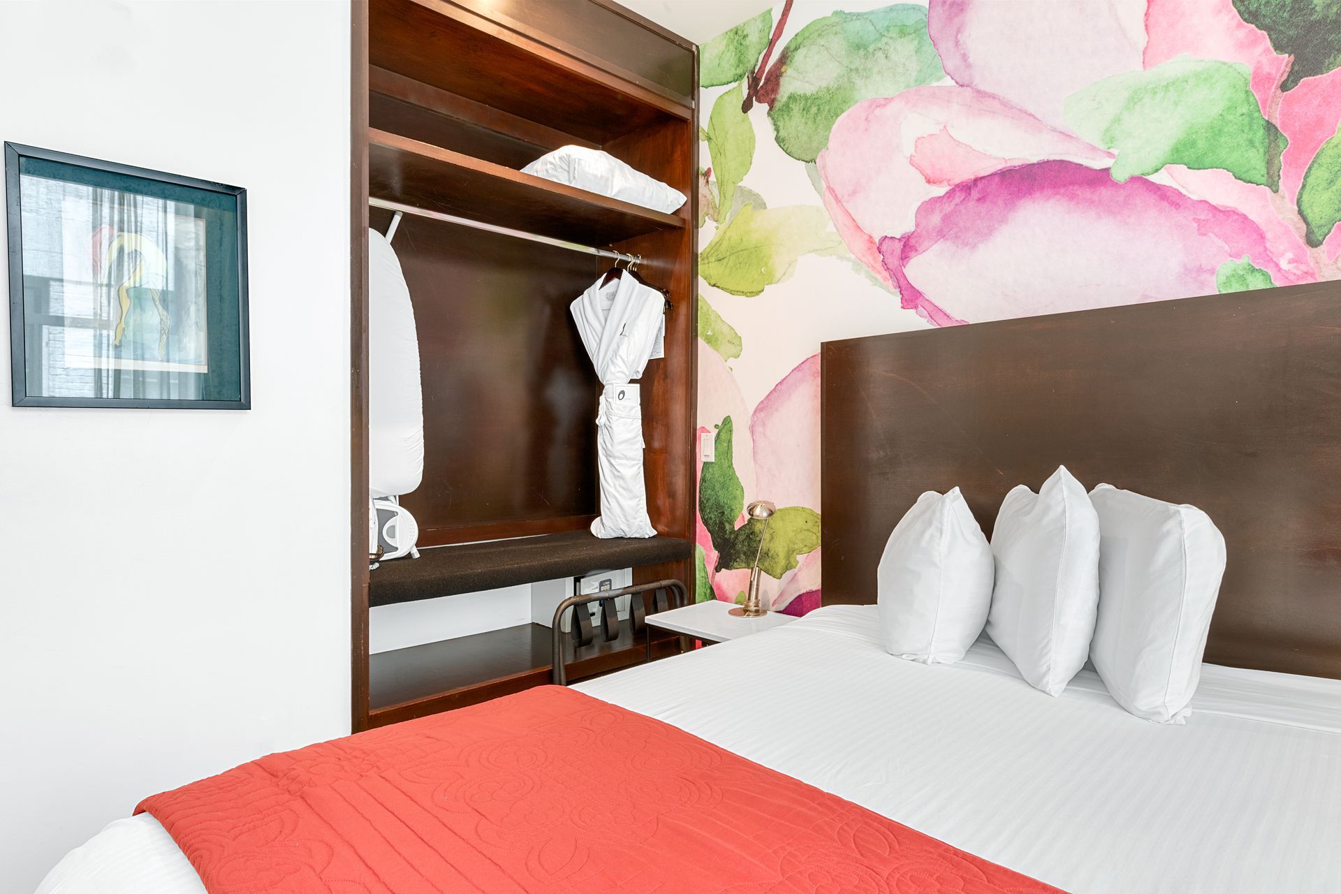 A hotel room with a king size bed and a floral wall mural.