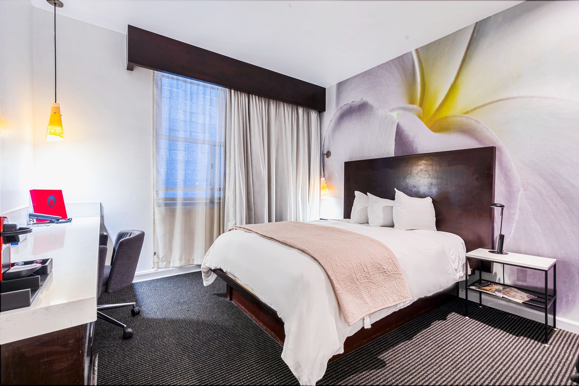 A hotel room with a large bed and a flower on the wall