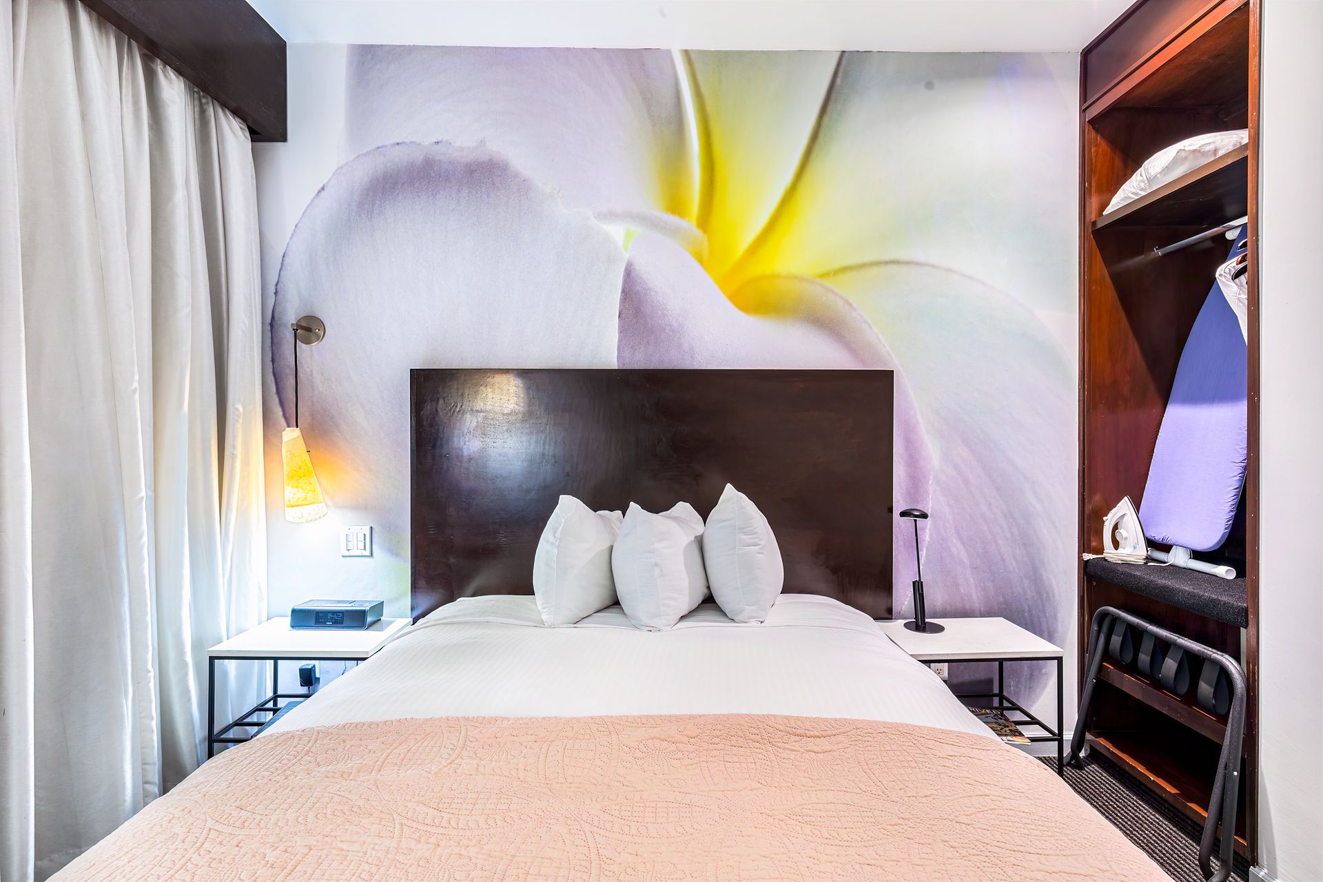 A hotel room with a bed and a picture of a flower on the wall.