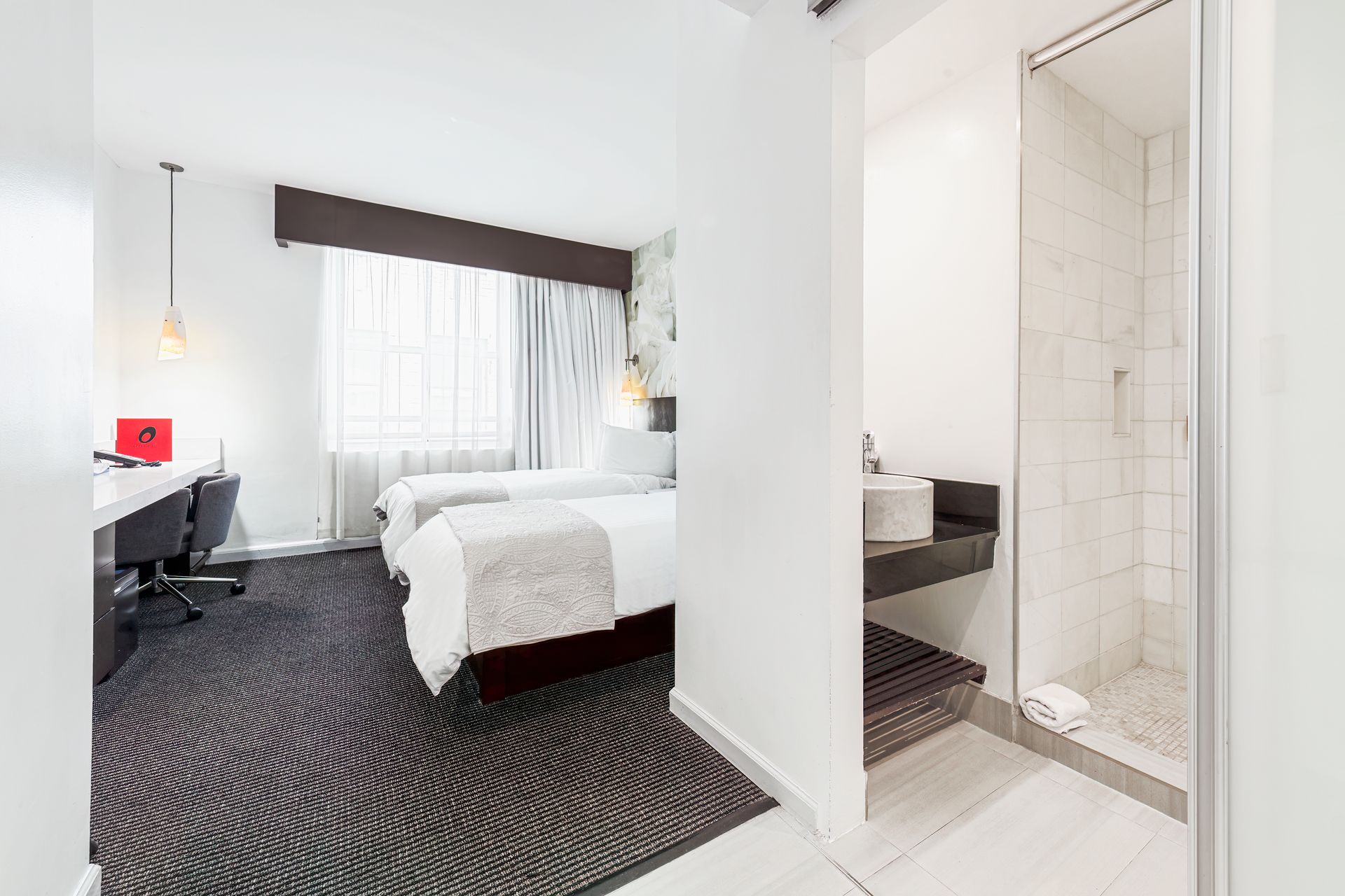 A hotel room with two beds , a desk , and a walk in shower.