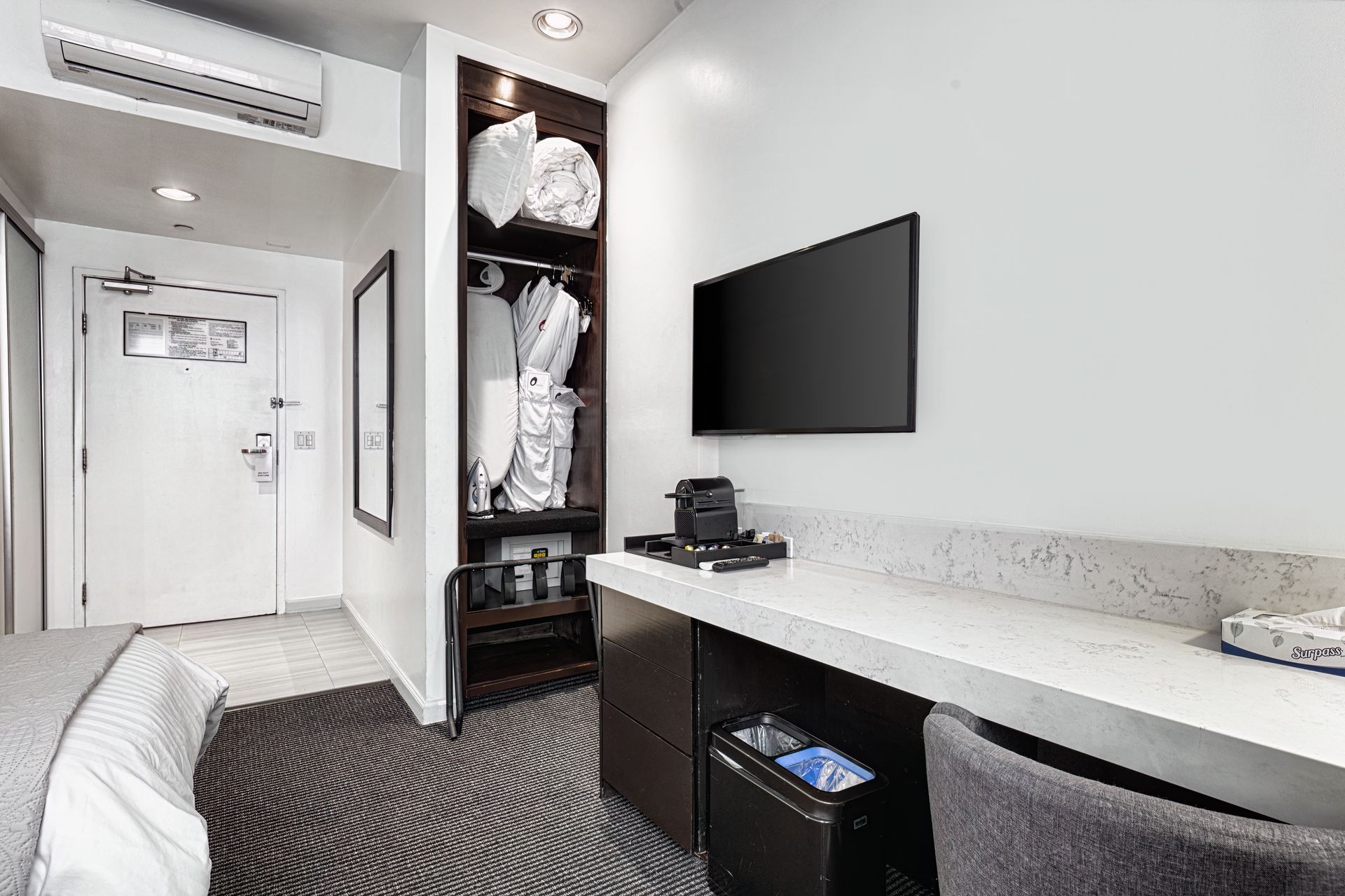 A hotel room with a bed , desk , chair and television.