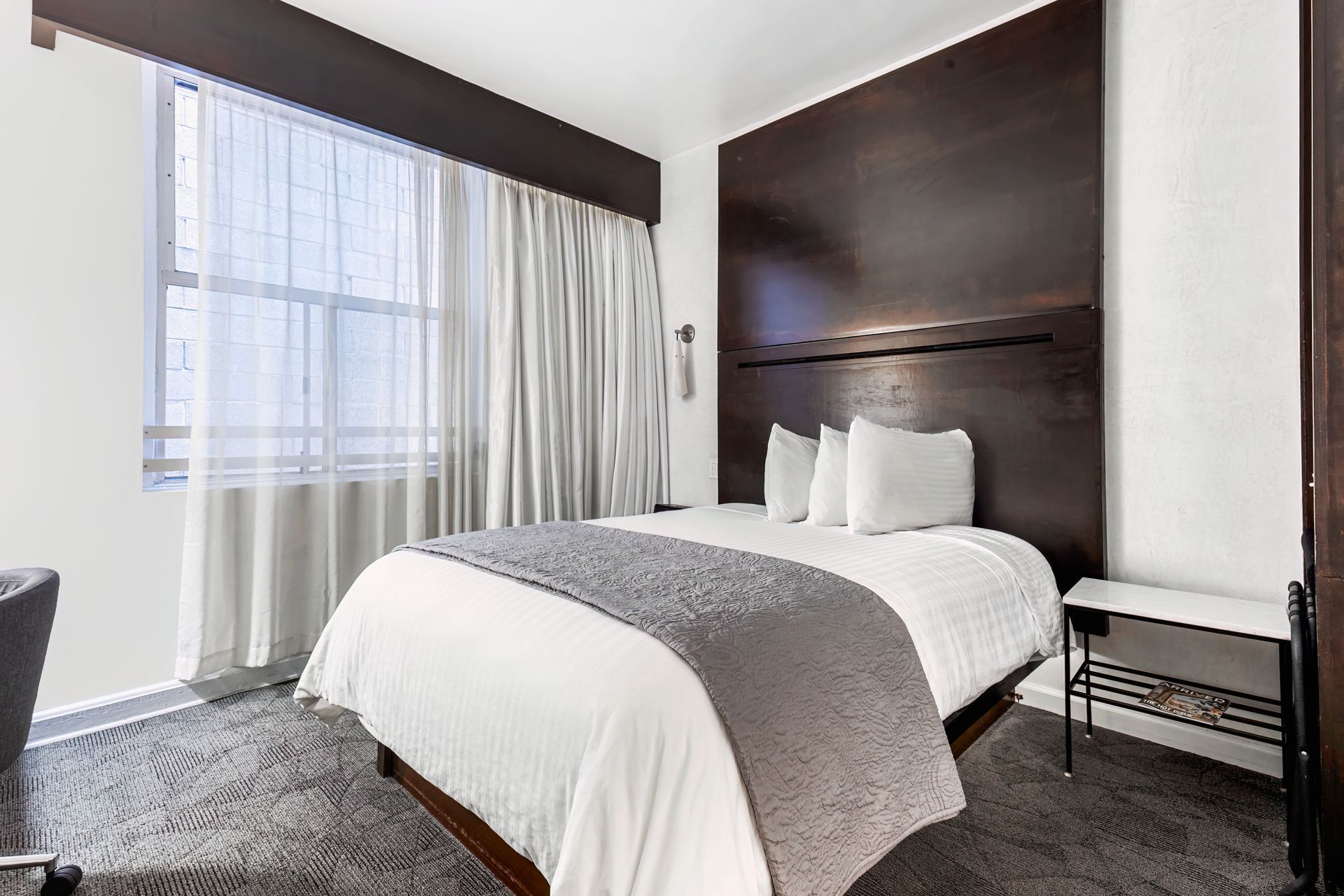 A hotel room with a king size bed and a large window.