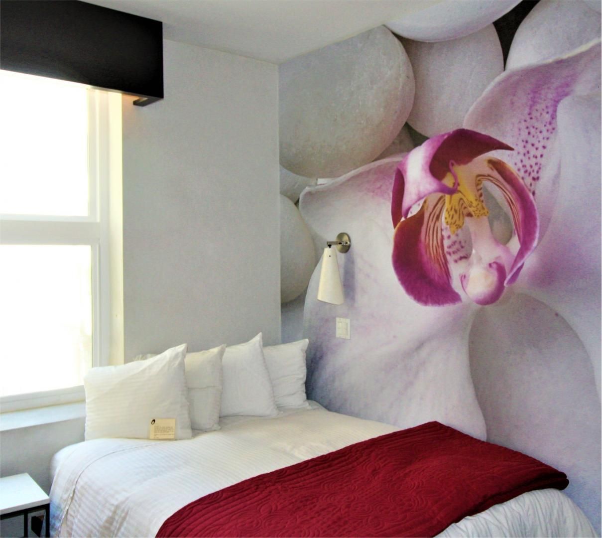 A bedroom with a bed and a picture of flowers on the wall