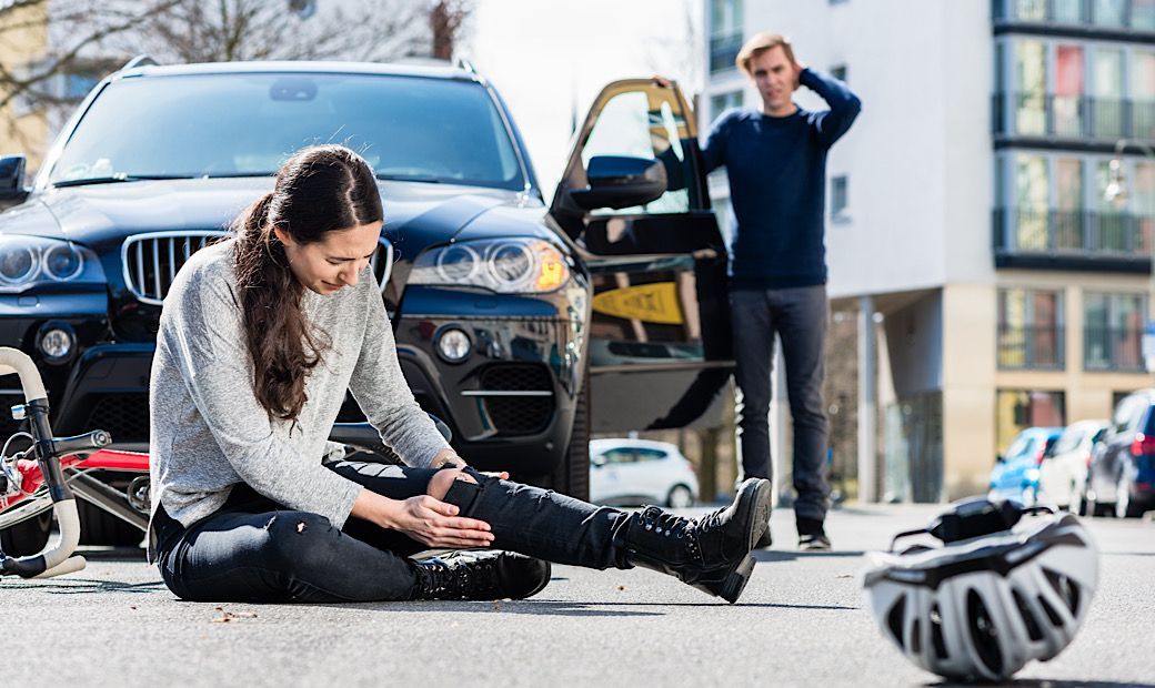 female bicyclist holding injured knee after auto accident