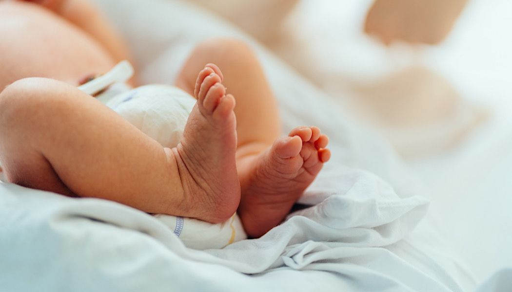 Newborn baby in hospital with close up of their sweet little feet. Ten little toes, two little feet on a hospital blanket.