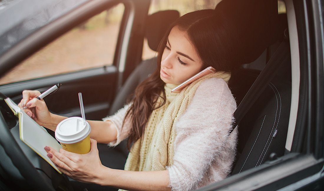 Woman on phone with coffee in hand, distracted while driving in Pittsburgh, PA